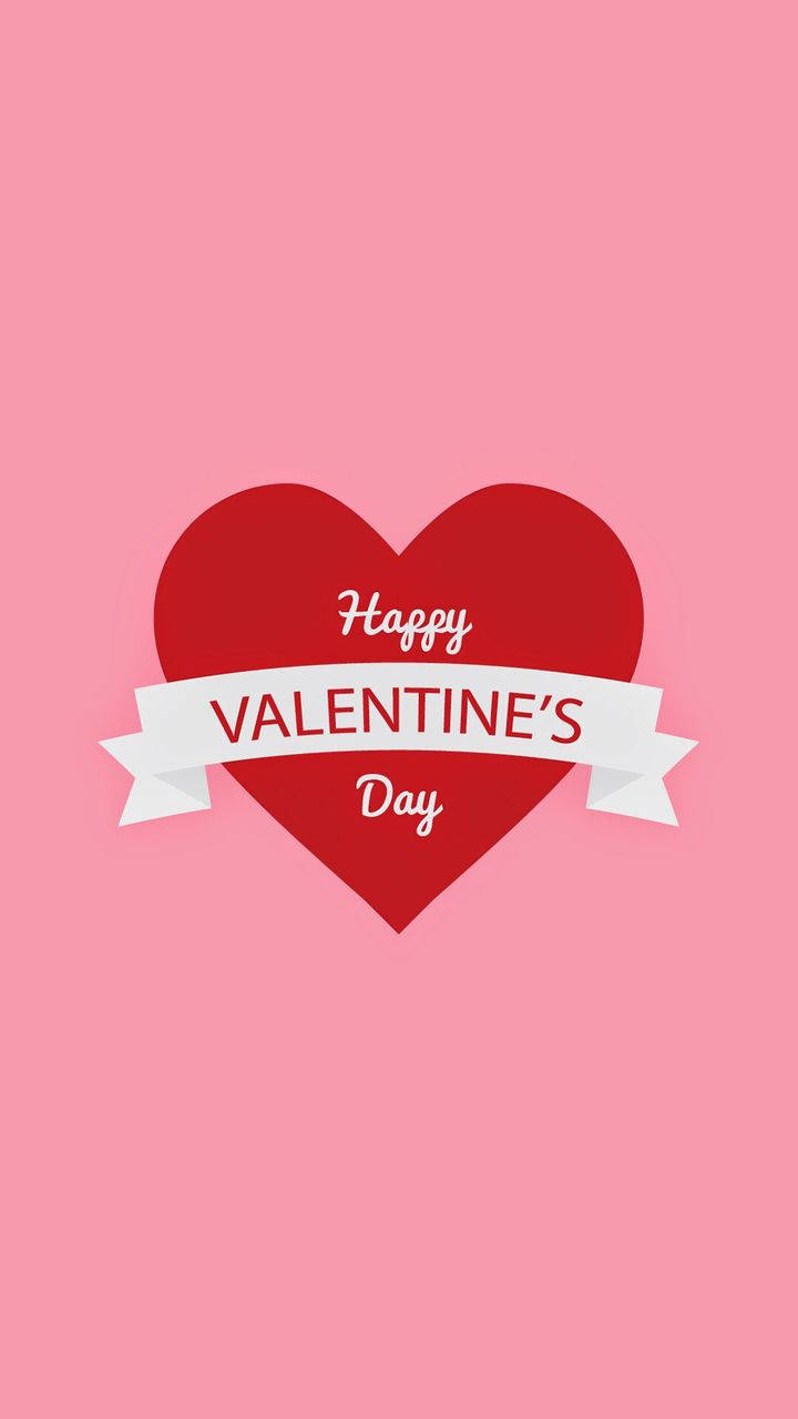 情人節 桌布 壁紙 — 一個大膽的紅色心形，帶有白色絲帶，上面寫著「Happy Valentine's Day」，置中在柔和的粉紅色背景上。