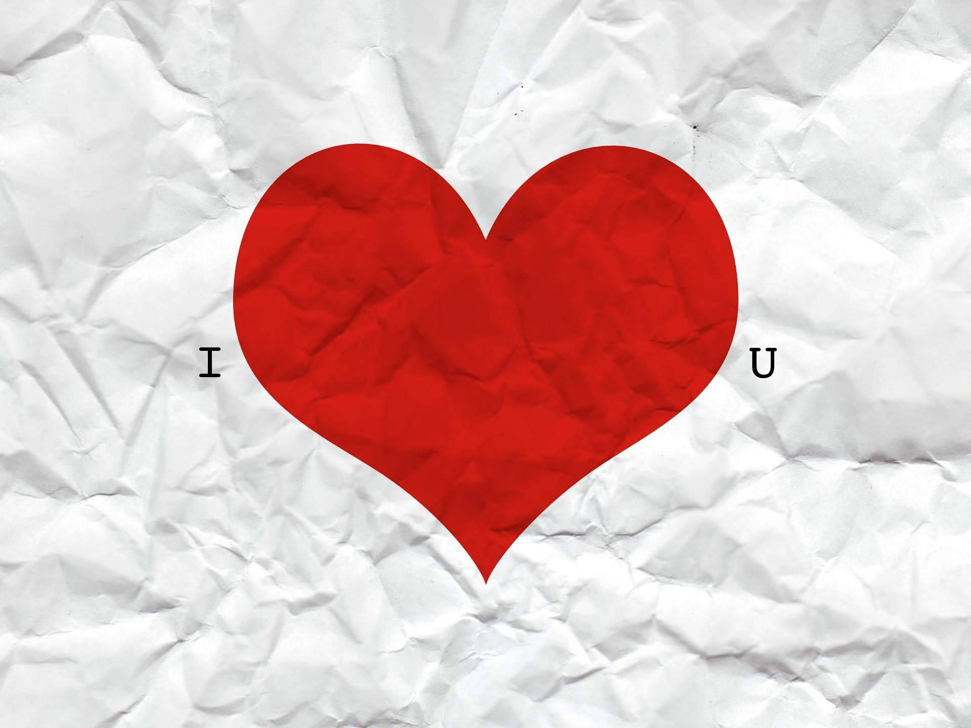 Tumblr Valentines Day 桌布 壁紙 — 一個大膽的紅色心形符號，上面有 'I' 和 'U' 字母，位於皺巴巴的白色紙張紋理上。