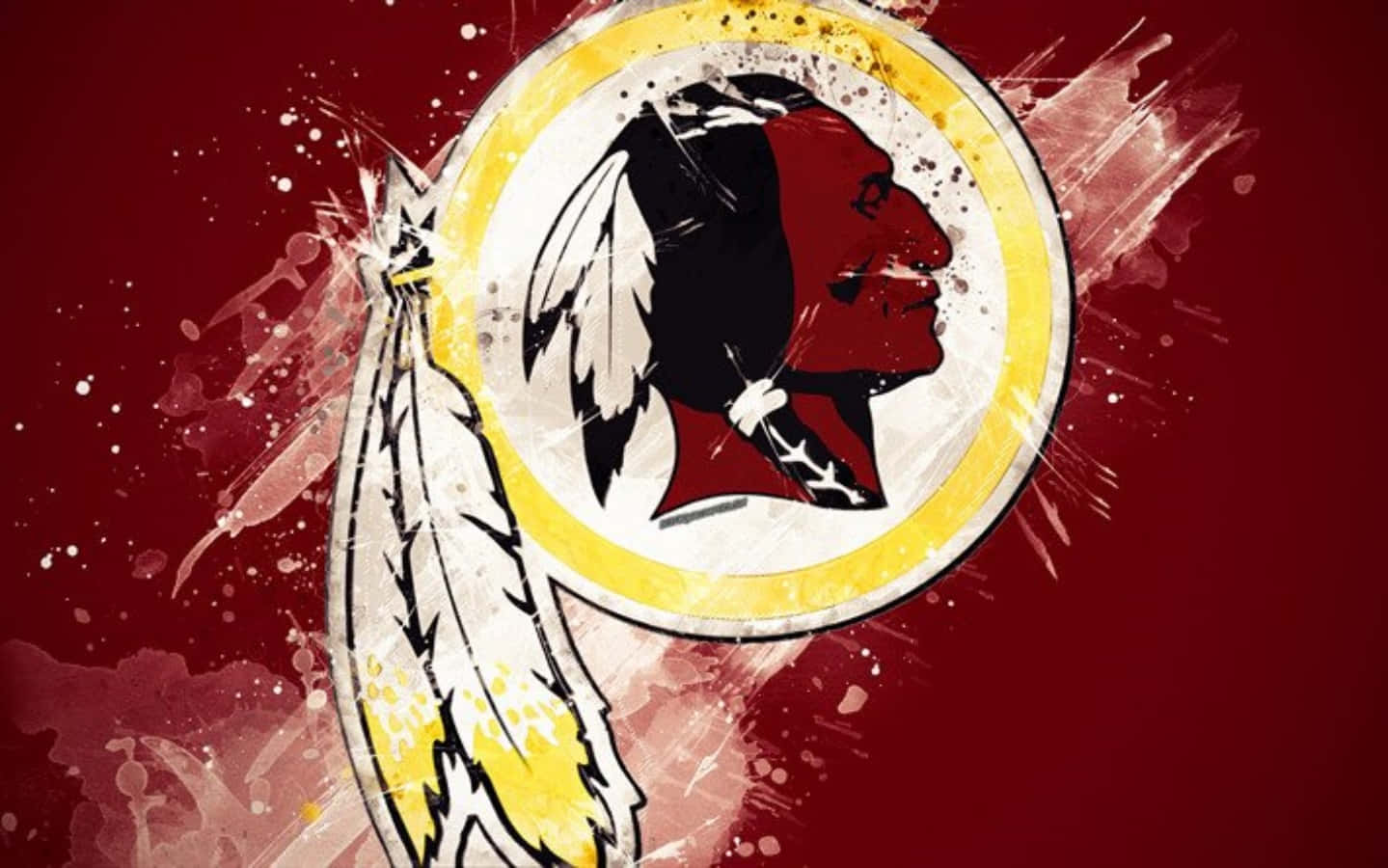 Washington Football 桌布 壁紙 — 一個大膽的華盛頓紅皮隊標誌，帶有美洲原住民側面和羽毛，背景是濺灑的紅色。