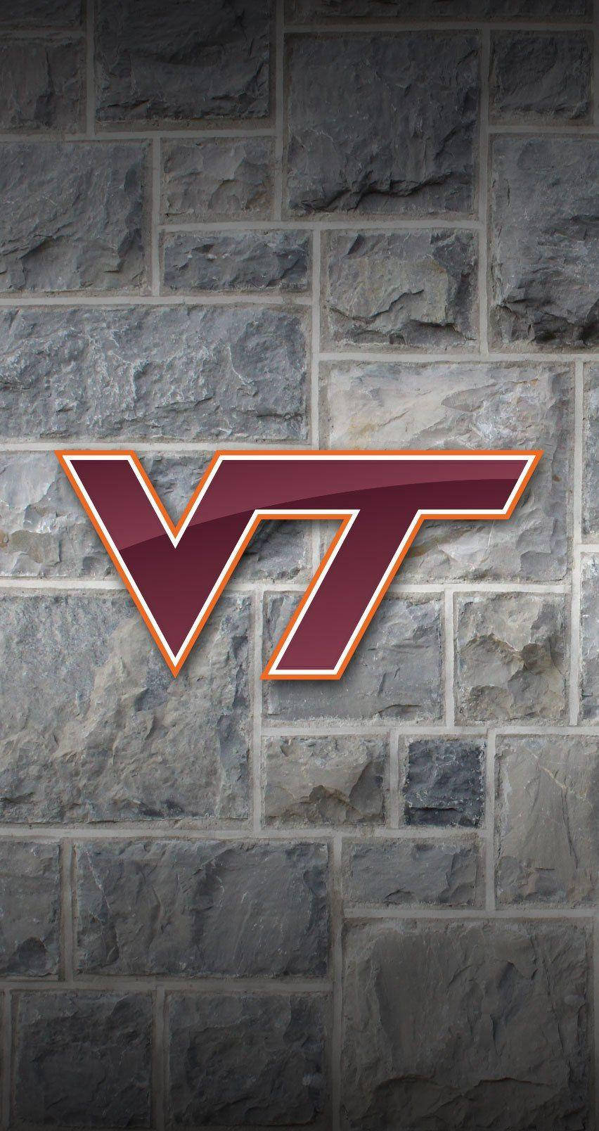 Virginia Tech 桌布 壁紙 — 一個大膽的酒紅色和橙色VT標誌，帶有光澤飾面，在紋理灰色石牆背景上脫穎而出。