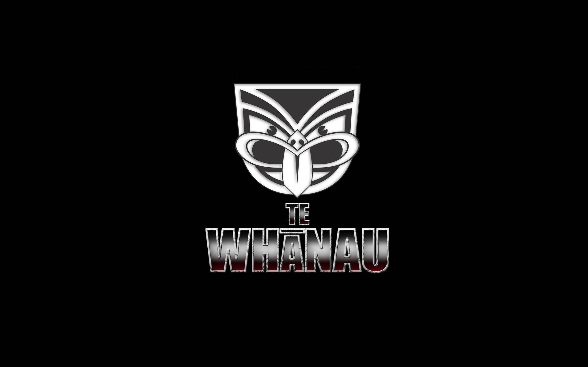 Nrl 桌布 壁紙 — 一個大膽的銀黑色毛利風格部落面具標誌，下方有 'TE WHĀNAU' 文字，置於純黑背景上。