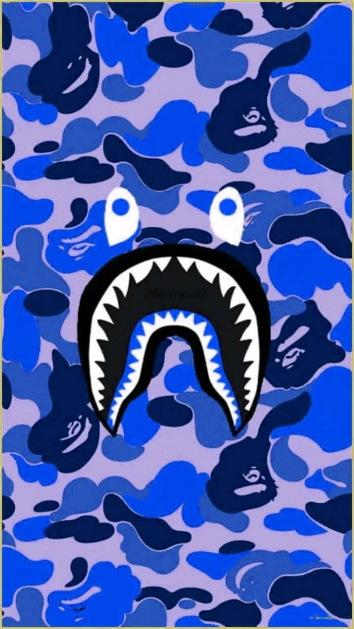 Bape 動態 桌布 壁紙 — 一個大膽的鯊魚臉，帶有鋒利的牙齒和白色的眼睛，從藍色和紫色的迷彩圖案中浮現。