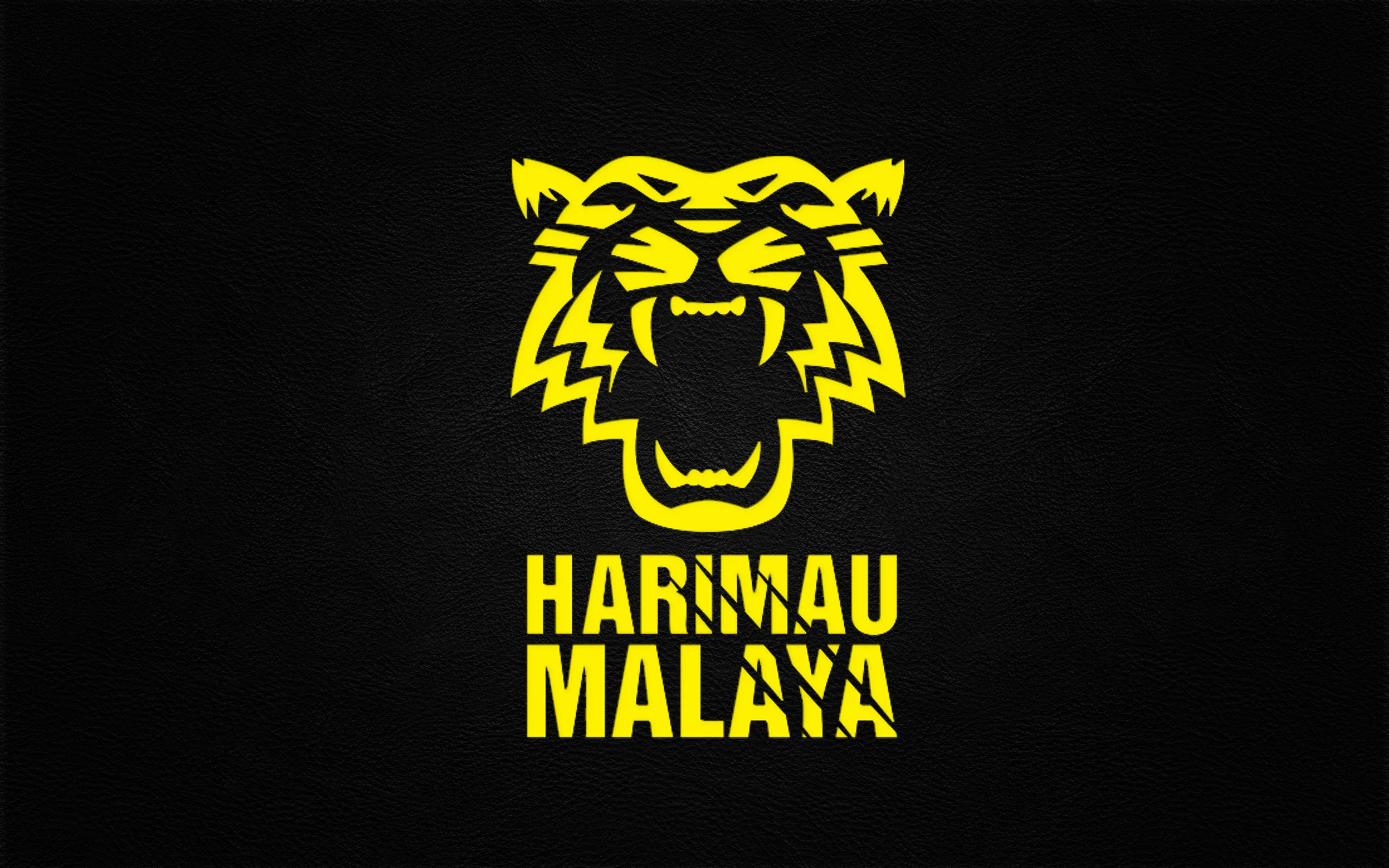 酷炫足球 桌布 壁紙 — 一個大膽的黃色風格化虎頭標誌，帶有「HARIMAU MALAYA」文字，位於紋理黑色皮革背景上。