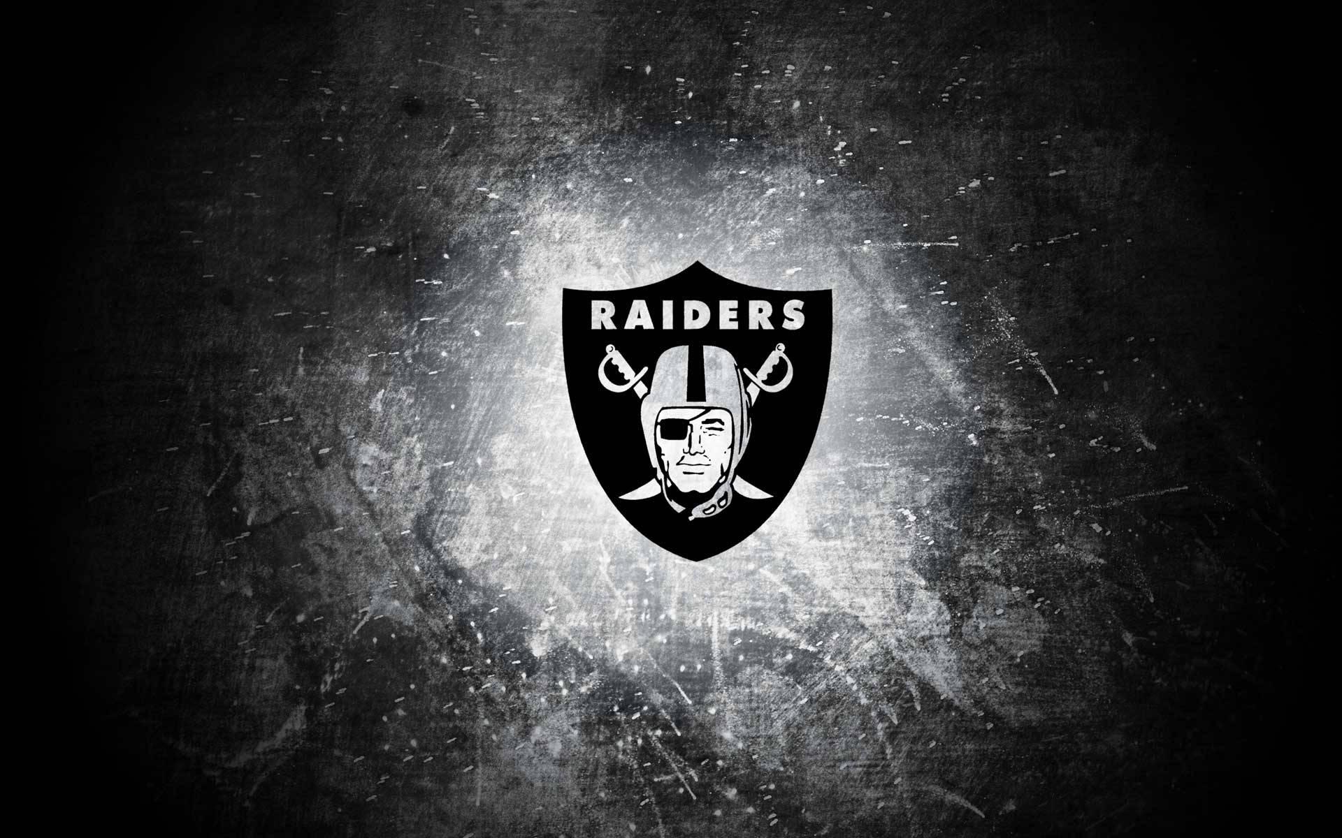 突襲者 桌布 壁紙 — 一個大膽的黑白 Raiders 標誌在粗糙紋理背景上發光，帶有光線條紋。