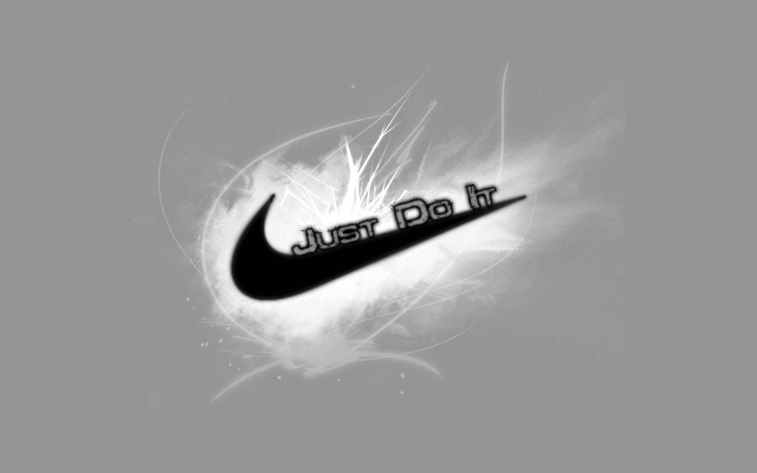 Cool Nike 桌布 壁紙 — 一個大膽的黑色Nike勾勾配上「Just Do It」文字，從灰色背景上的動態白色能量爆發中浮現。