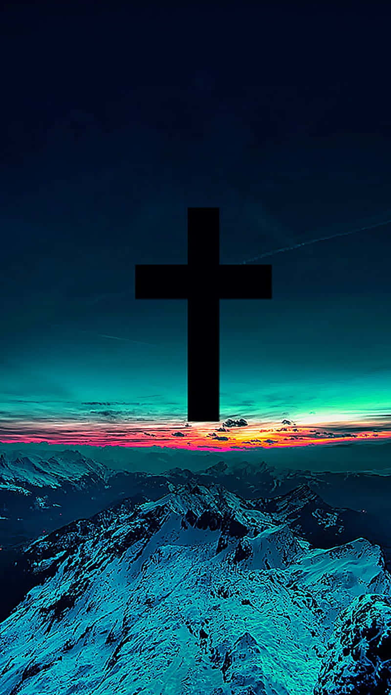 Jesus iPhone 桌布 壁紙 — 一個大膽的黑色十字架在雪覆蓋的山脈上，映襯著充滿活力的日落天空。