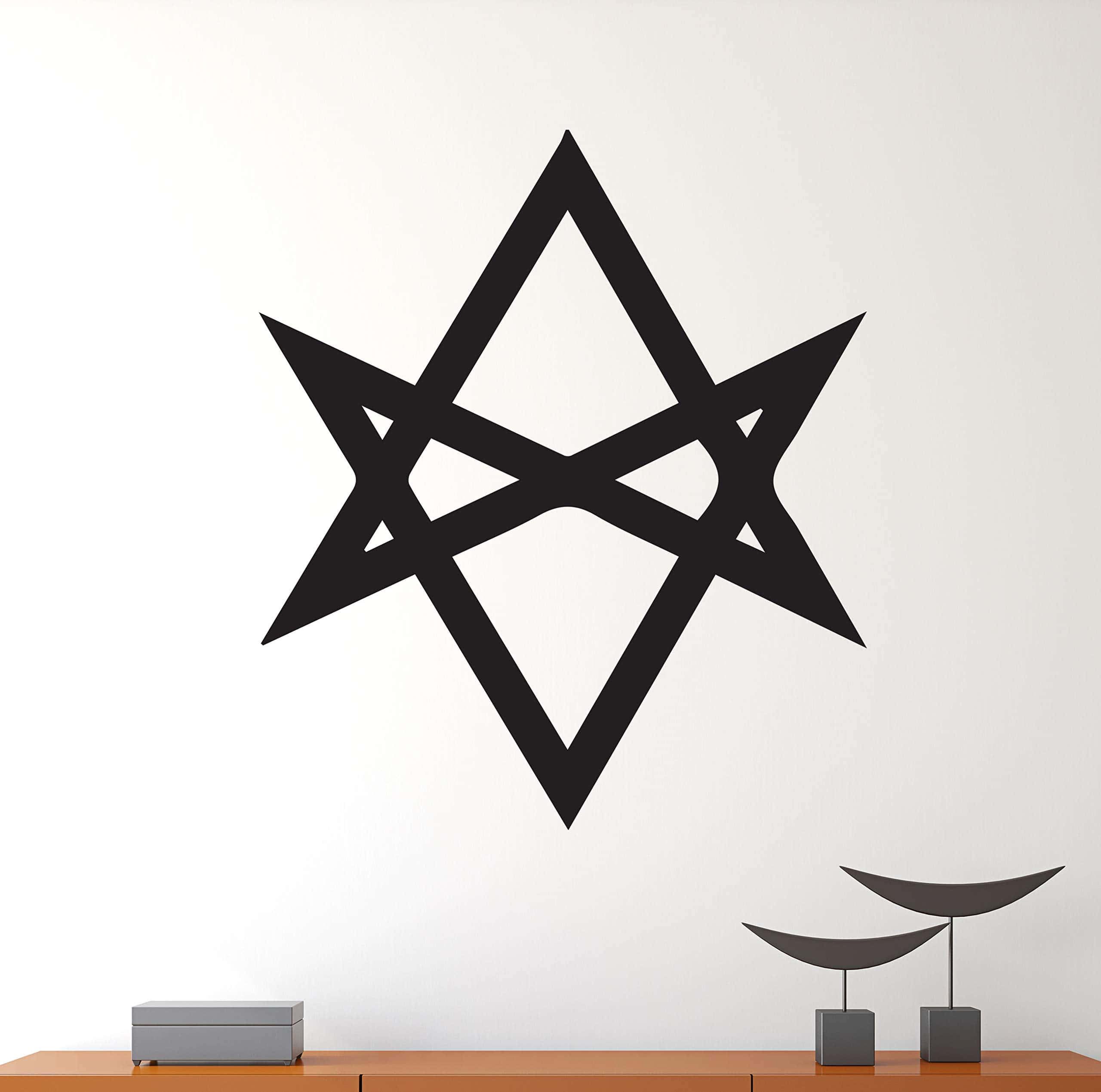 Thelema 桌布 壁紙 — 一個大膽的黑色幾何星形貼紙裝飾在一個樸素的白色牆壁上，牆壁上方有一個木架，上面擺放著極簡的灰色裝飾。