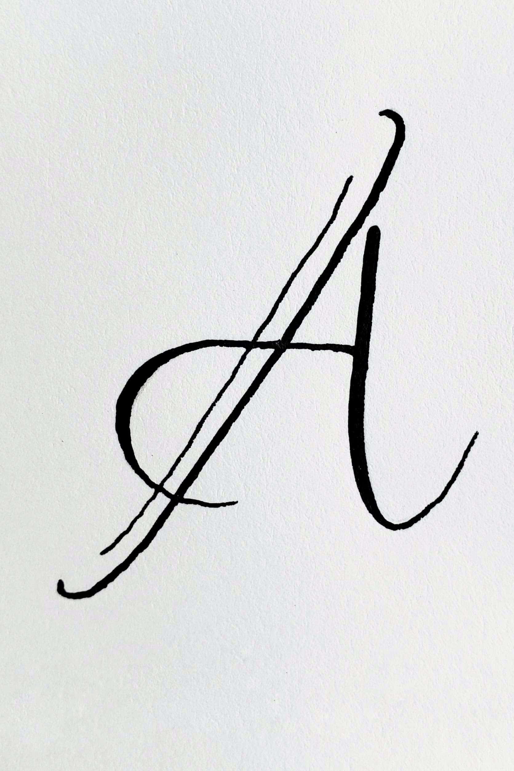 A 桌布 壁紙 — 一個大膽的黑色書法字母A，在帶有紋理的白色紙張上以富有表現力的筆觸優雅地勾勒出來。