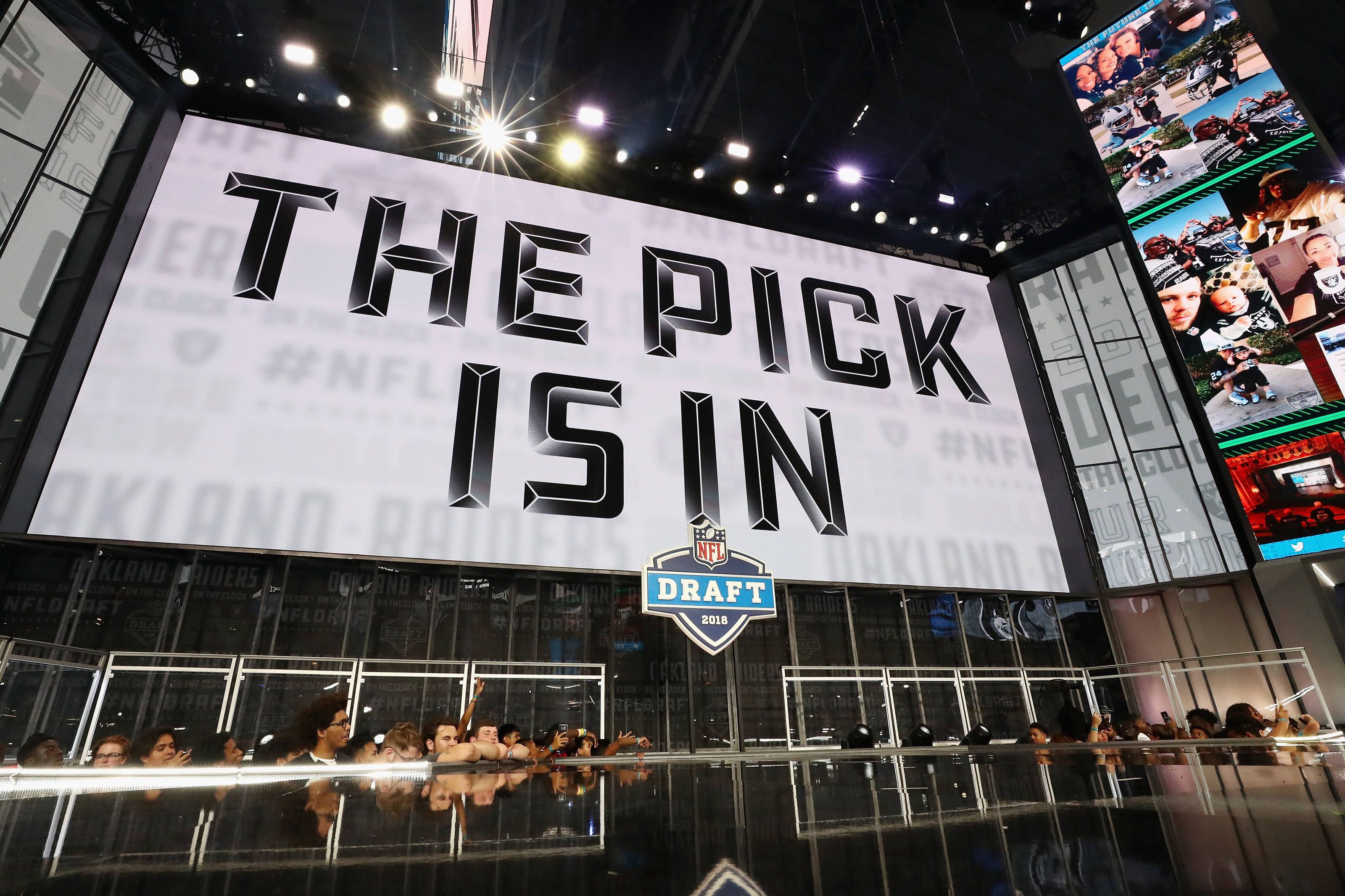 運動 桌布 壁紙 — 一個大螢幕在2018年NFL選秀舞台上顯示「THE PICK IS IN」，下方有粉絲在明亮的燈光下歡呼。