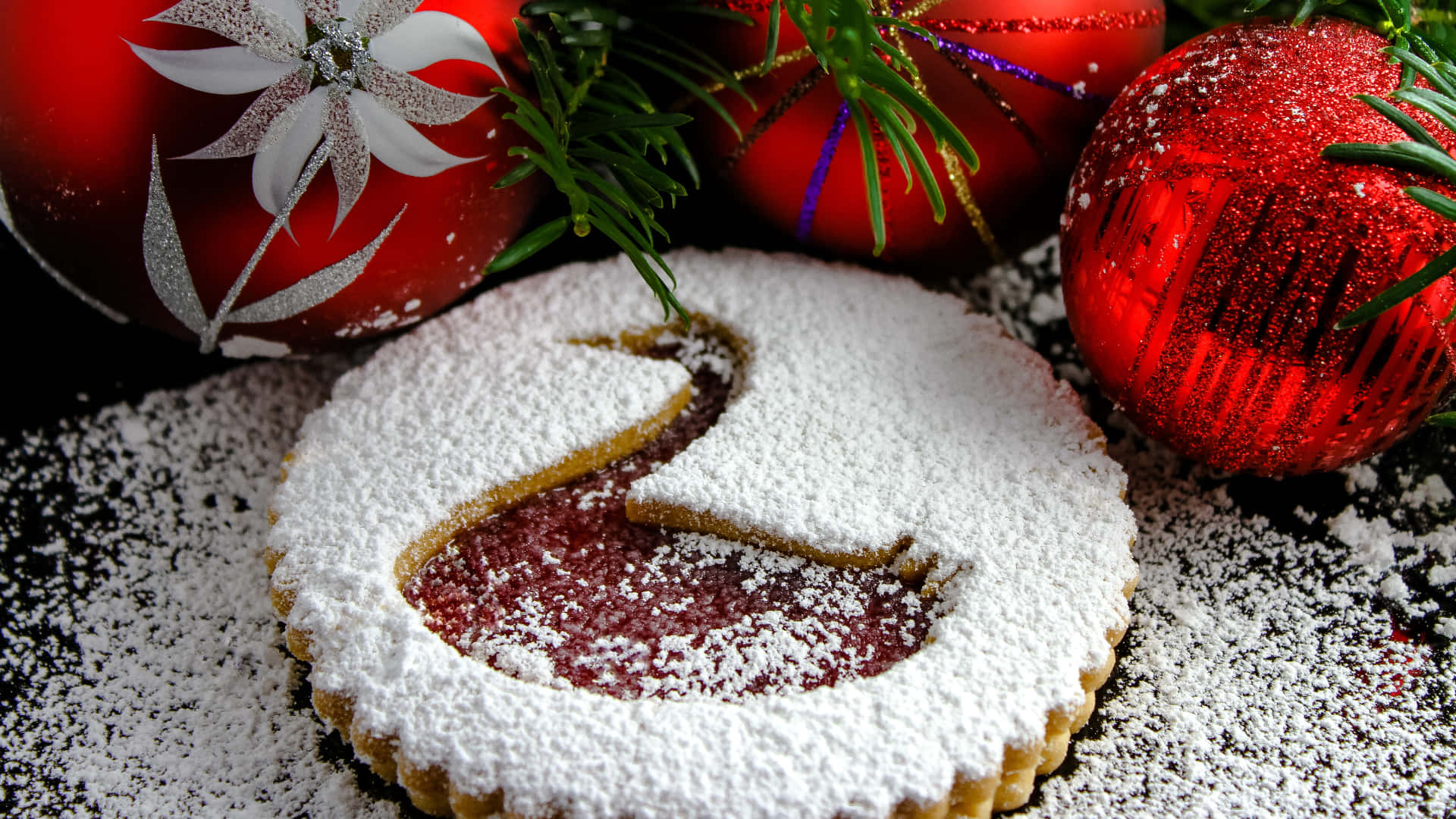 Pastry 桌布 壁紙 — 一個天鵝形狀的聖誕餅乾，撒上糖粉，旁邊放著閃閃發光的紅色裝飾品和松針。