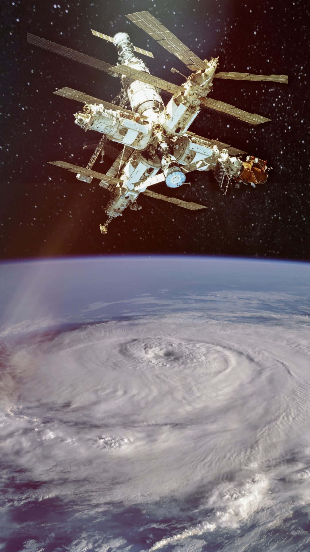 Live Space 桌布 壁紙 — 一個太空站在地球彎曲地平線上空盤旋的巨大颶風上方運行。