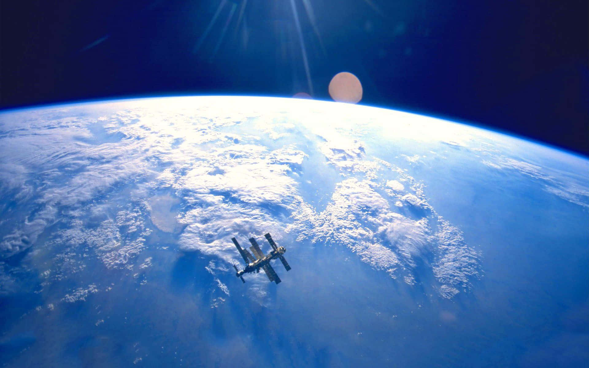 Satellite 桌布 壁紙 — 一個太空站繞地球運行，陽光穿透大氣層，雲層在下方旋轉。