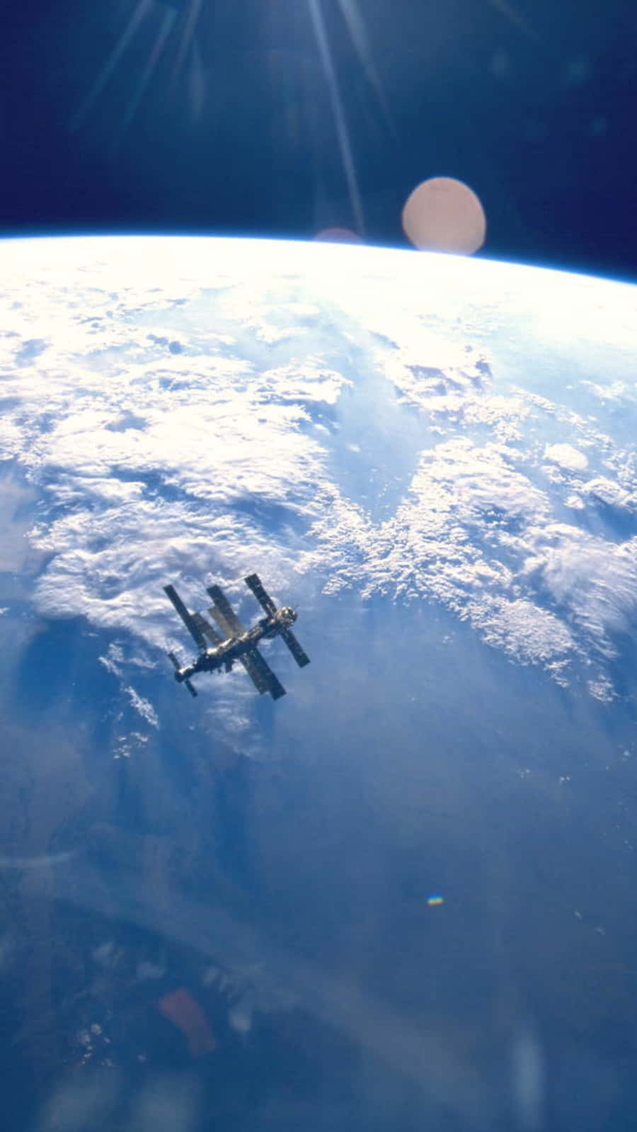 Iss 桌布 壁紙 — 一個太空站繞地球運行，陽光穿透雲層，下方有一顆發光的行星。