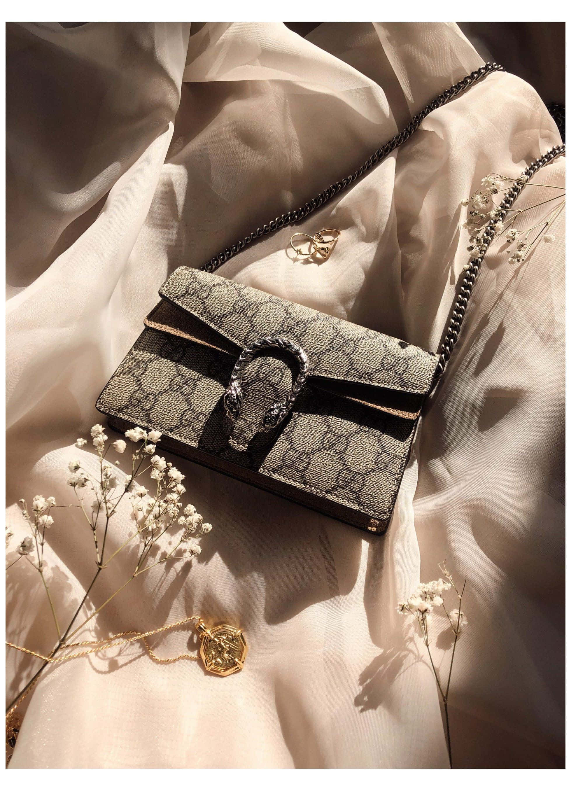 purse 桌布 壁紙 — 一個奢華的Gucci Dionysus手袋優雅地放在柔軟的奶油色布料上，旁邊有乾花和金飾，在溫暖的陽光下。