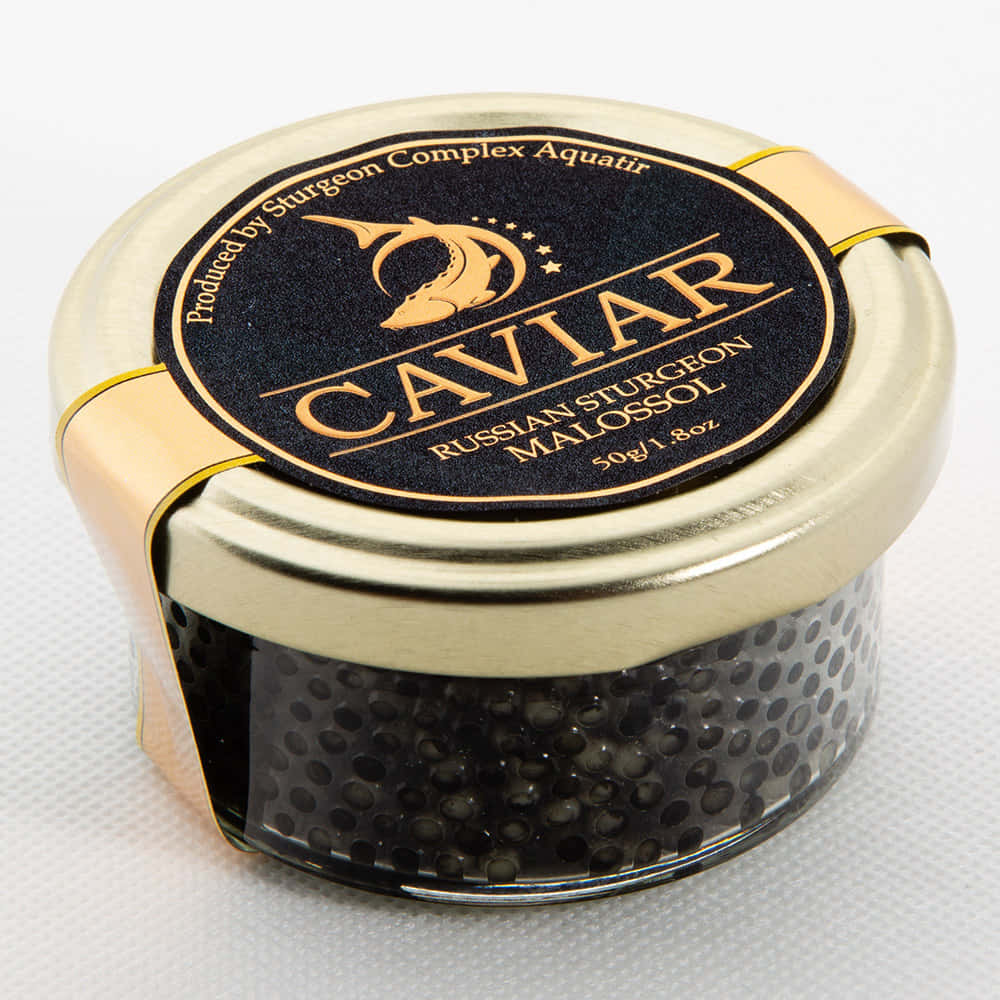 Black Caviar 桌布 壁紙 — 一個奢華的俄羅斯鱘魚子醬罐，帶有金色蓋子和黑色標籤，放置在白色紋理表面上。