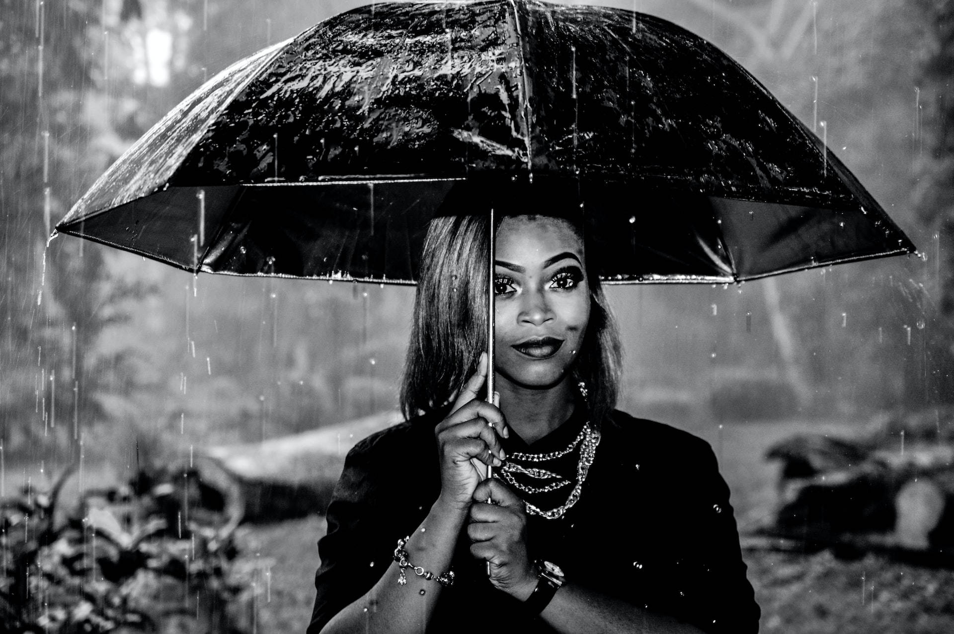 Woman 桌布 壁紙 — 一個女人在雨中撐著一把黑色雨傘，是一幅充滿氣氛的黑白人像。