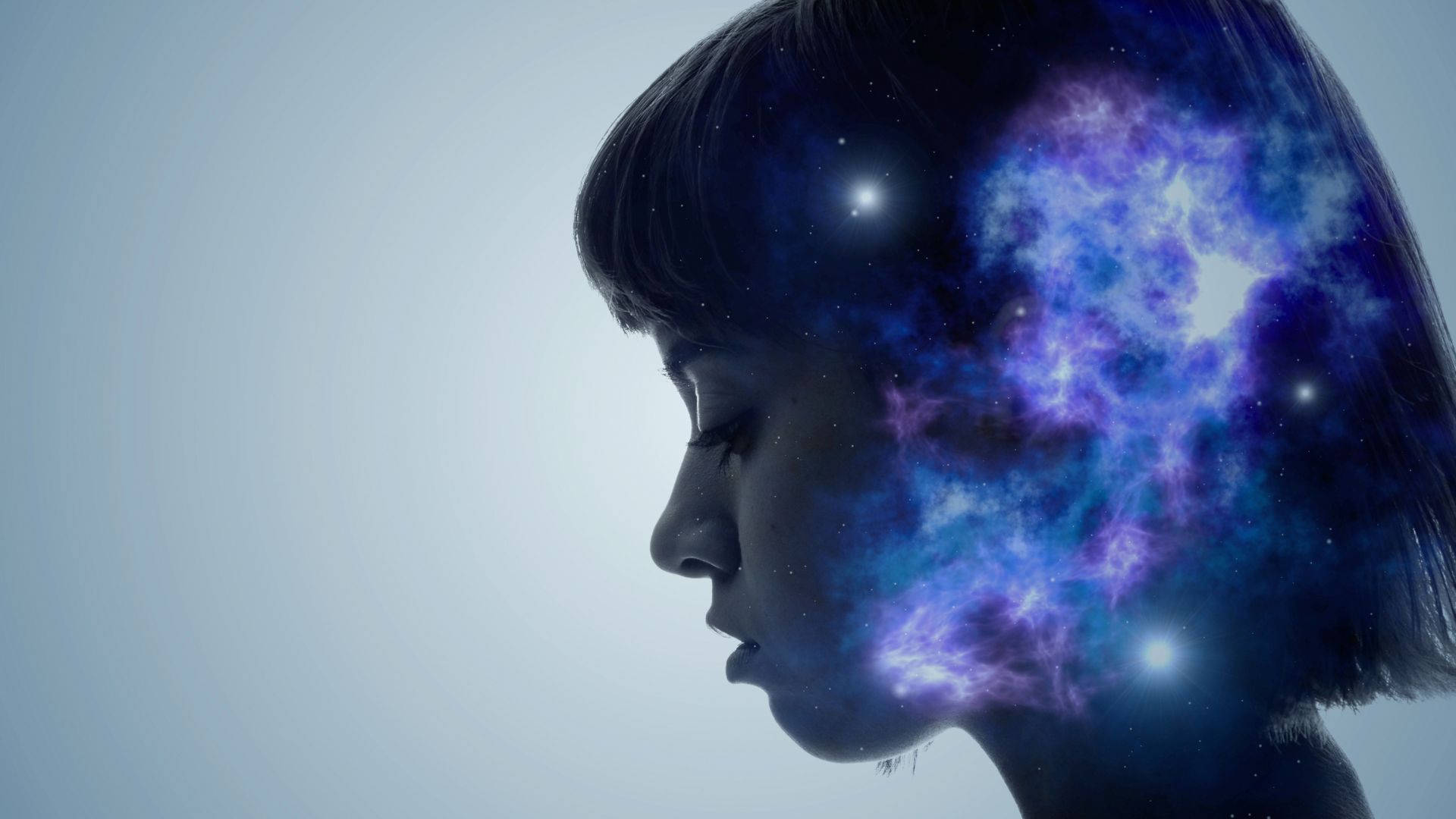 mind 桌布 壁紙 — 一個女人的側面，她的頭髮和頭部內有發光的宇宙星雲在旋轉，背景是柔和的藍色。