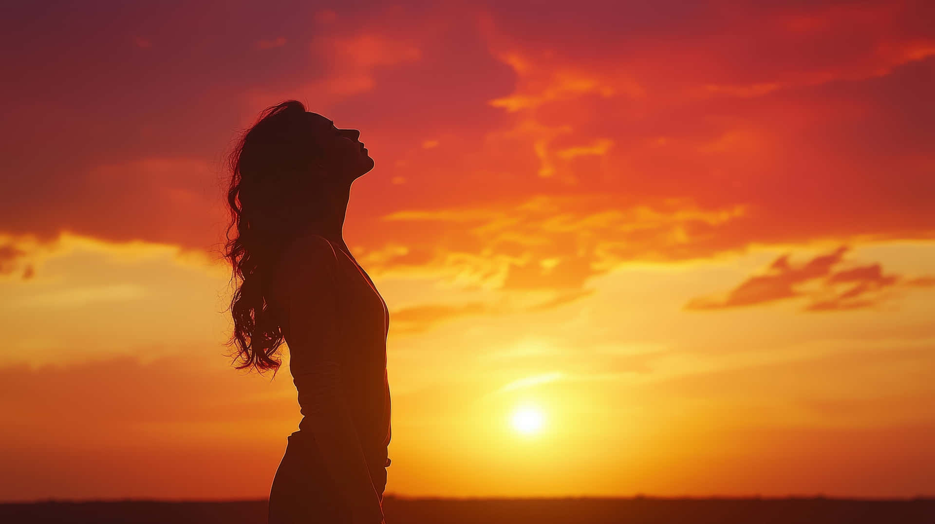 Woman Standing at Sunset in Reflective Pose 壁紙 — 一個女人的剪影，頭向後傾斜，映襯著火紅的橙色和紅色日落天空。