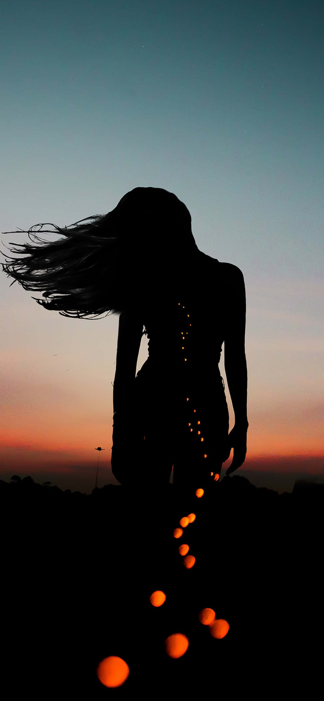 Silhouette 桌布 壁紙 — 一個女人的剪影，頭髮飄逸，背景是黃昏天空，發光球體從她手中拖曳而出。