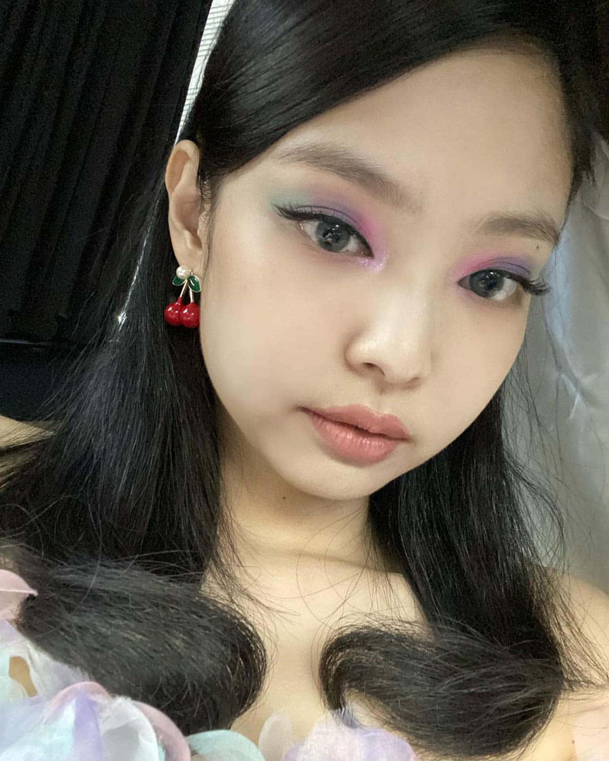 BLACKPINK 桌布 壁紙 — 一個女人的特寫肖像，她化了大胆的粉彩眼影，戴著櫻桃耳環，背景是深色窗簾。