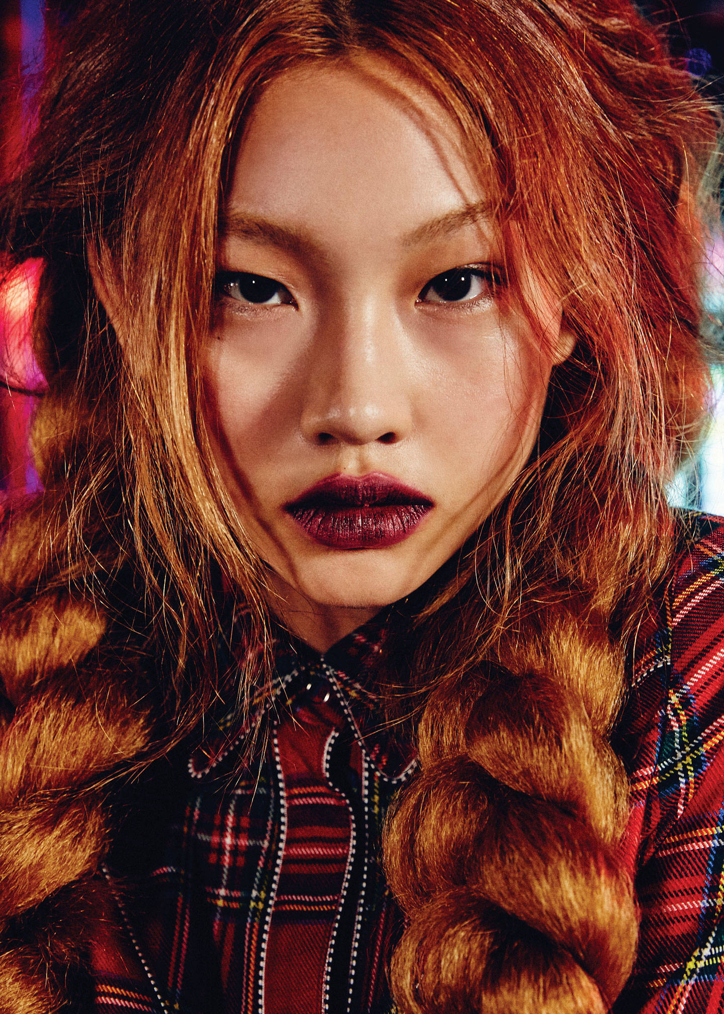 Hoyeon 桌布 壁紙 — 一個女人的特寫肖像，她有著火紅的頭髮，梳成粗辮子，塗著大膽的深色口紅，背景是色彩繽紛的模糊背景。