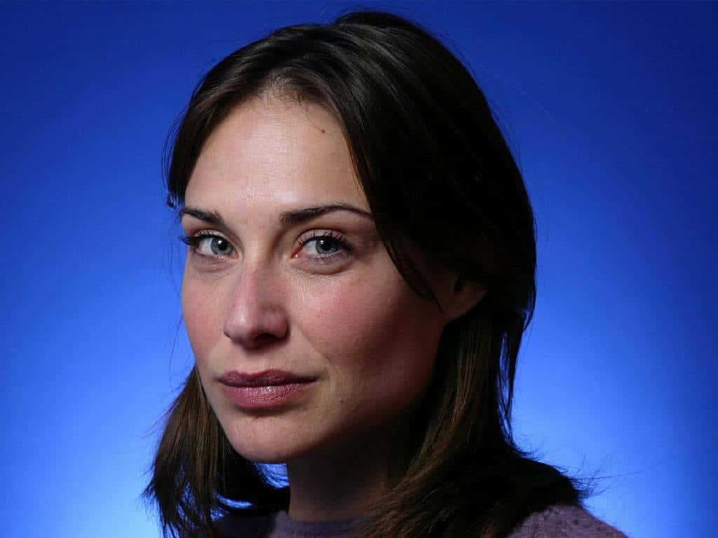 Claire Forlani 桌布 壁紙 — 一個女人的特寫肖像，棕色頭髮和藍色眼睛，背景為純藍色。
