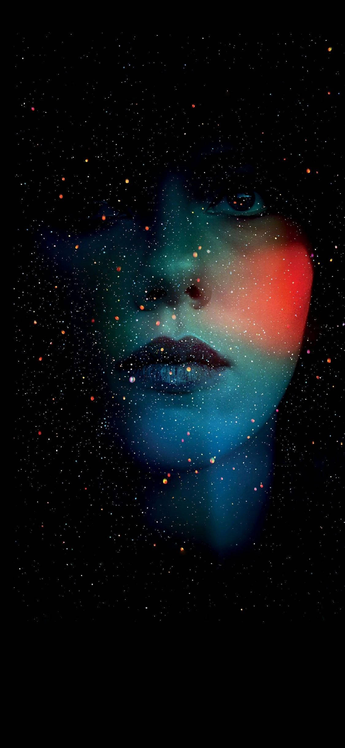 手機 桌布 壁紙 — 一個女人的臉從宇宙星辰中浮現，帶有發光的藍色和紅色色調，背景是黑色虛空。