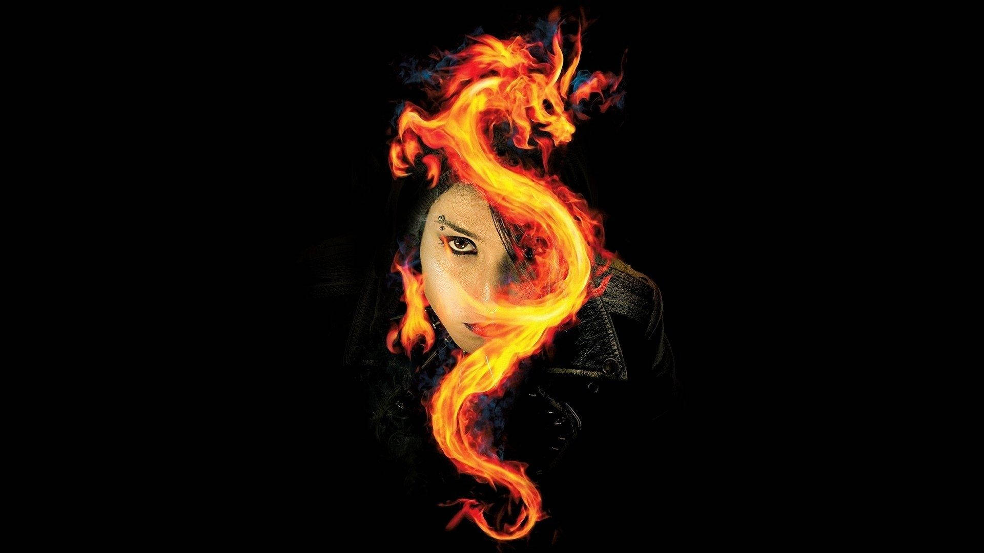 Fire Girl 桌布 壁紙 — 一個女人的臉從黑色背景中旋轉的火焰中浮現，眼睛發出強烈的光芒，一條火龍纏繞在她的頭上。