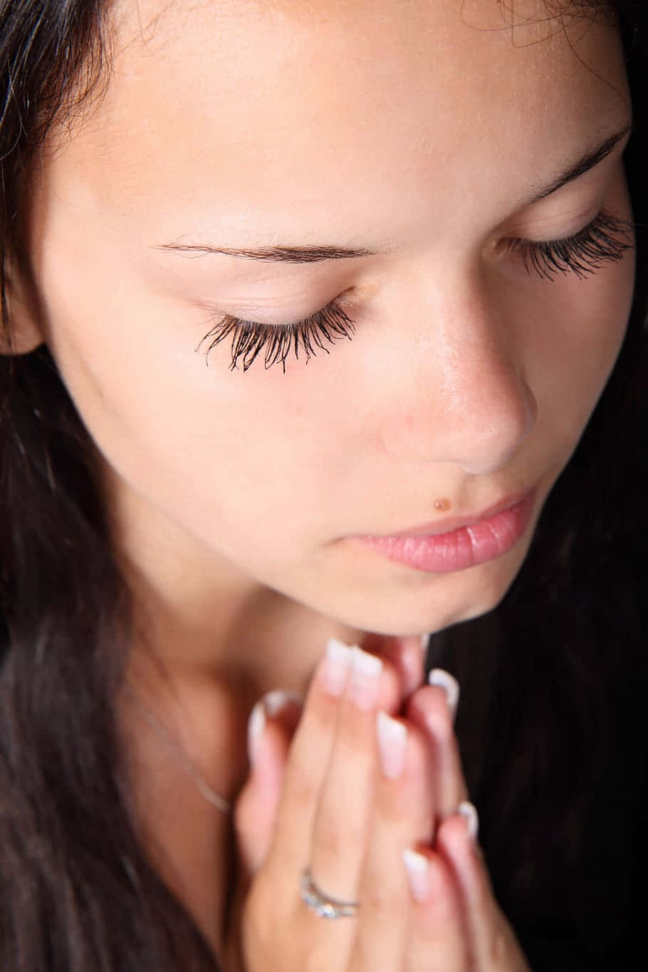 Praying 桌布 壁紙 — 一個女人閉上眼睛，雙手合十祈禱，背景深色的特寫。