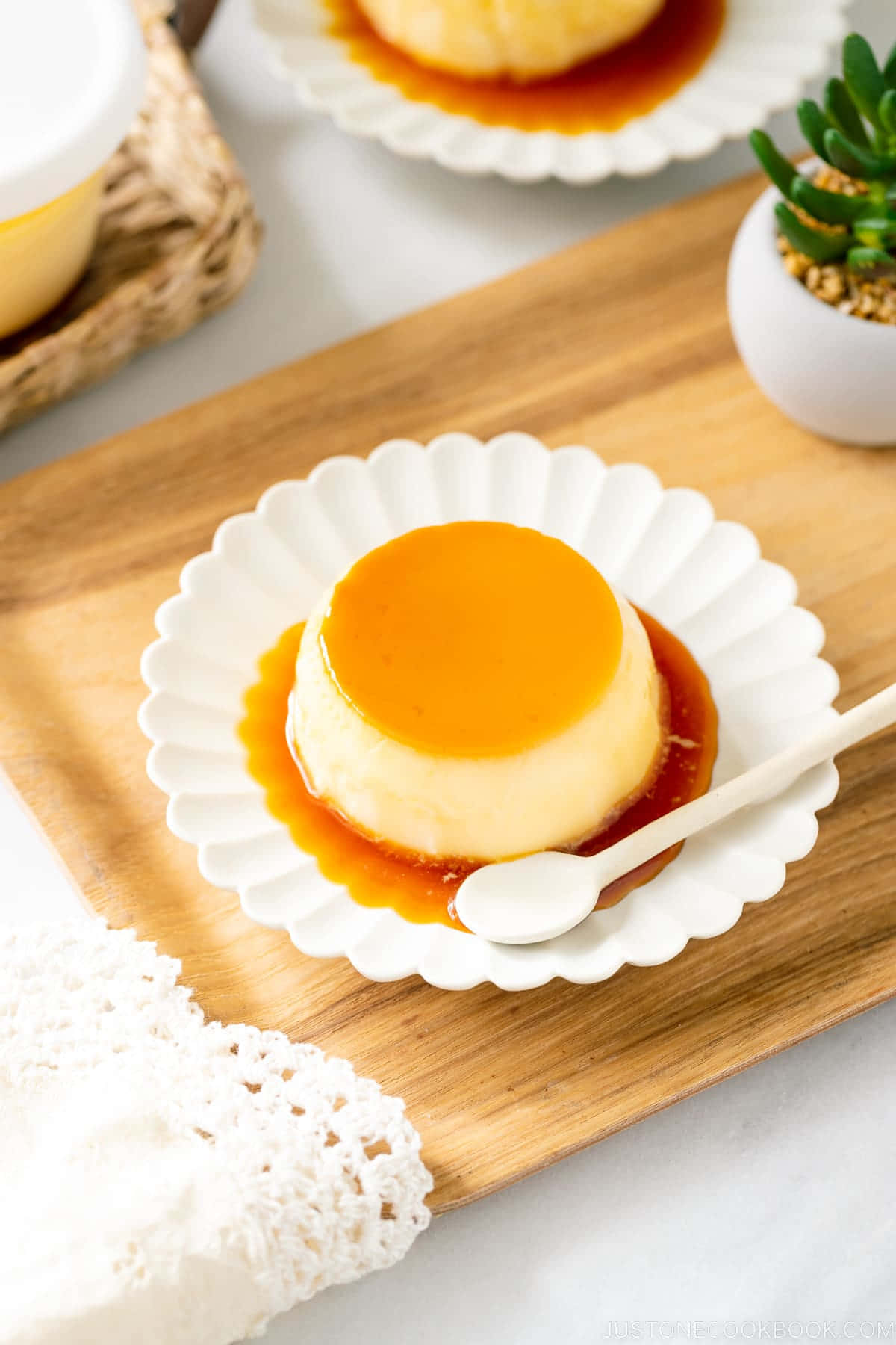 Japanese Sweets 桌布 壁紙 — 一個奶油焦糖布丁甜點在白色波浪紋盤上閃閃發光，放在木板上，旁邊有精緻的蕾絲餐巾。