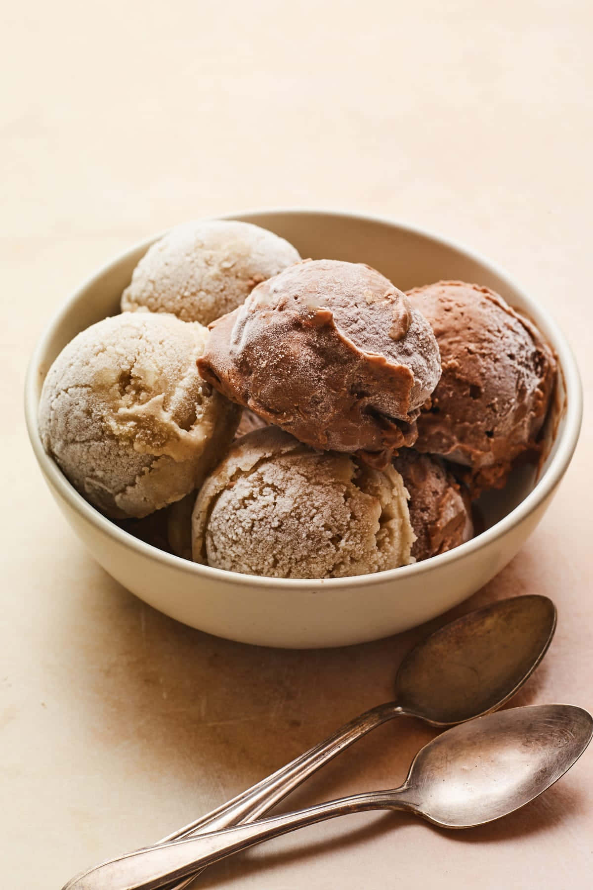 Ice Cream 桌布 壁紙 — 一個奶油碗裝著巧克力和香草冰淇淋球，撒上可可粉，旁邊有兩把復古湯匙。