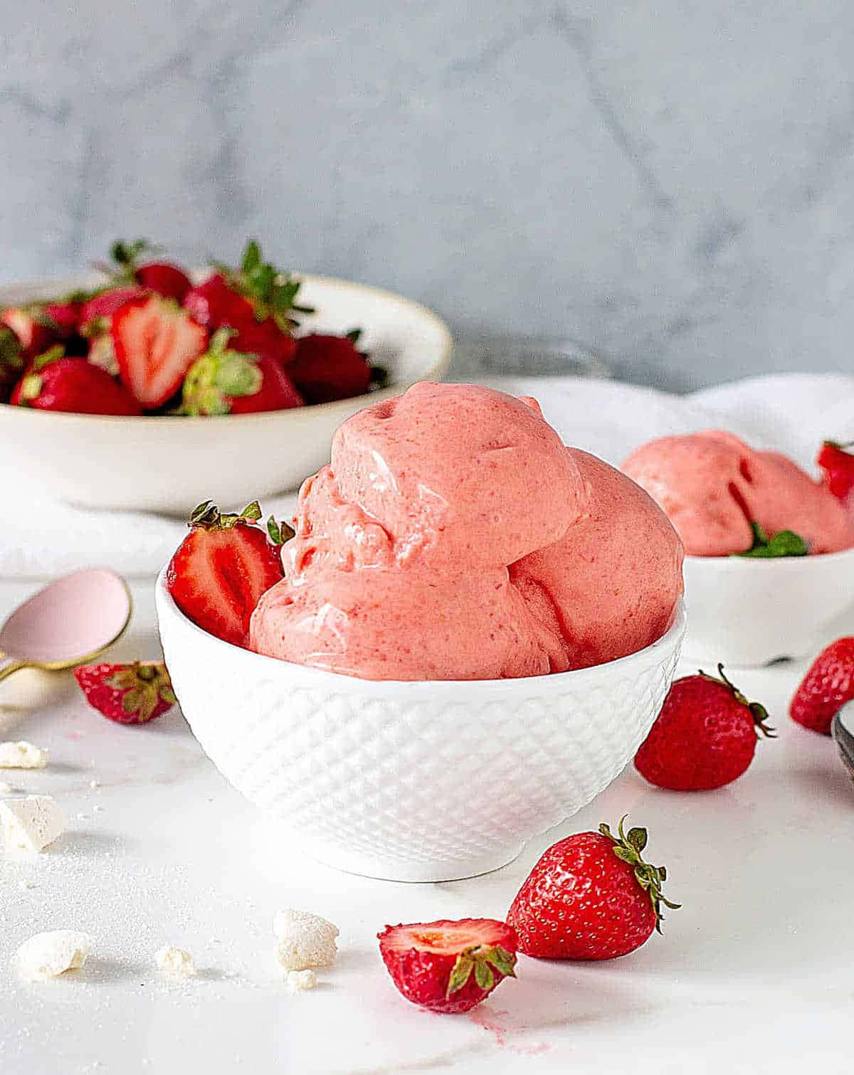 Strawberries 桌布 壁紙 — 一個奶油粉紅草莓冰淇淋球放在白色紋理碗中，周圍是新鮮完整和切半的草莓，置於潔白表面上。