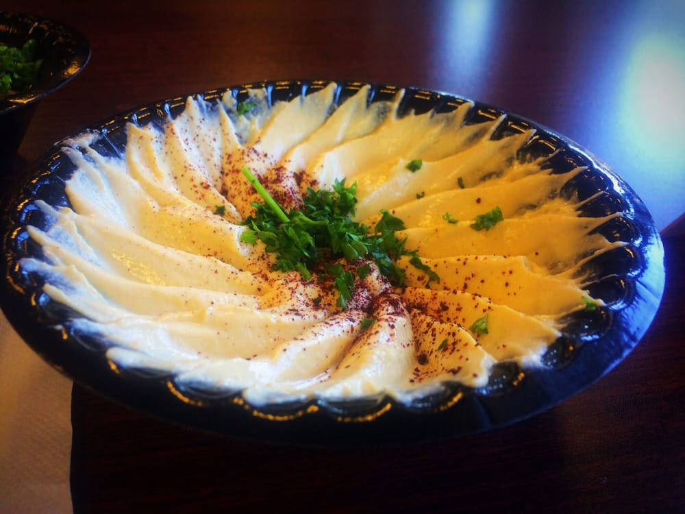 Food Photography 桌布 壁紙 — 一個奶油鷹嘴豆泥在深色波浪碗中巧妙地扇形展開，上面撒有紅椒粉和新鮮歐芹。