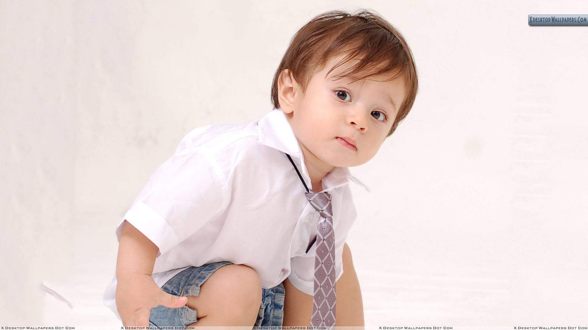 Boy 桌布 壁紙 — 一個好奇的幼兒，穿著白色襯衫和圖案領帶，坐在純白背景前，表情嚴肅。