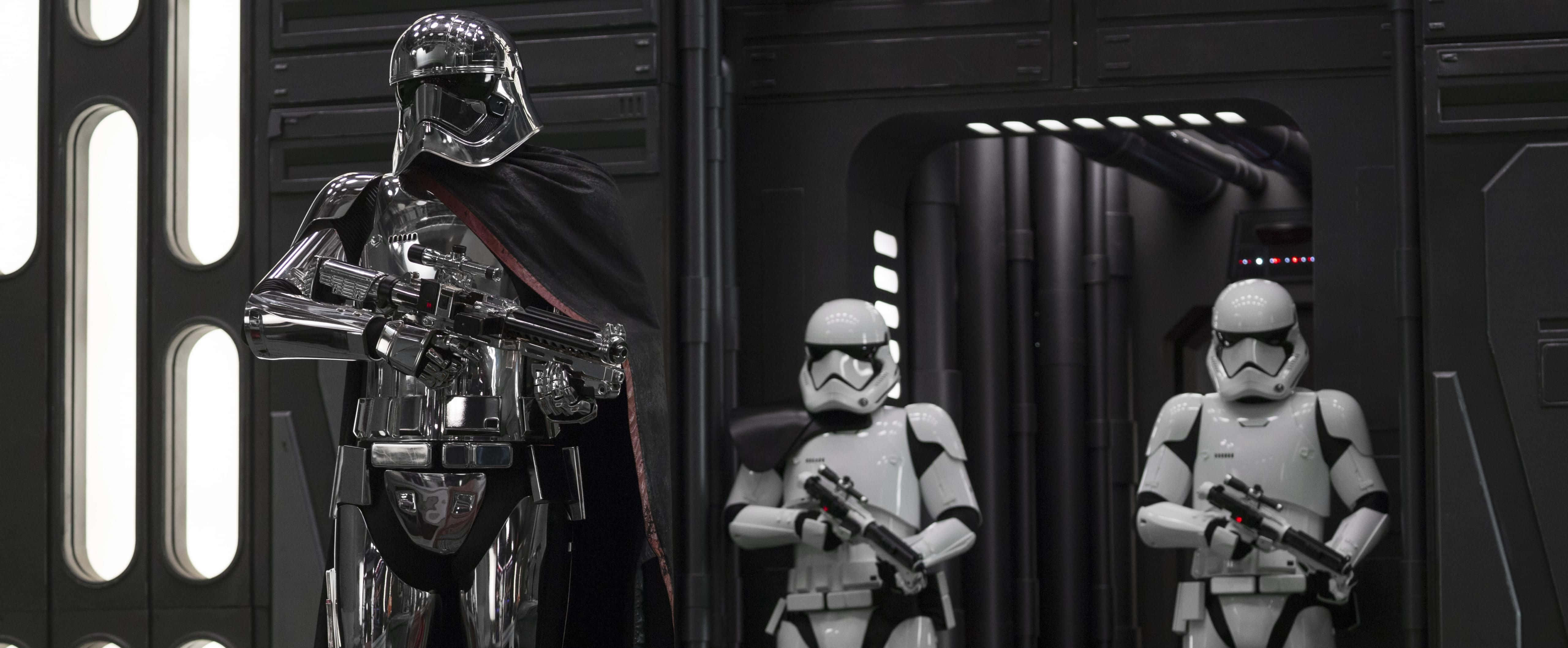 Captain Phasma 桌布 壁紙 — 一個威脅性的達斯維達與兩名風暴兵站在一個昏暗的未來主義走廊中，帶有發光面板。