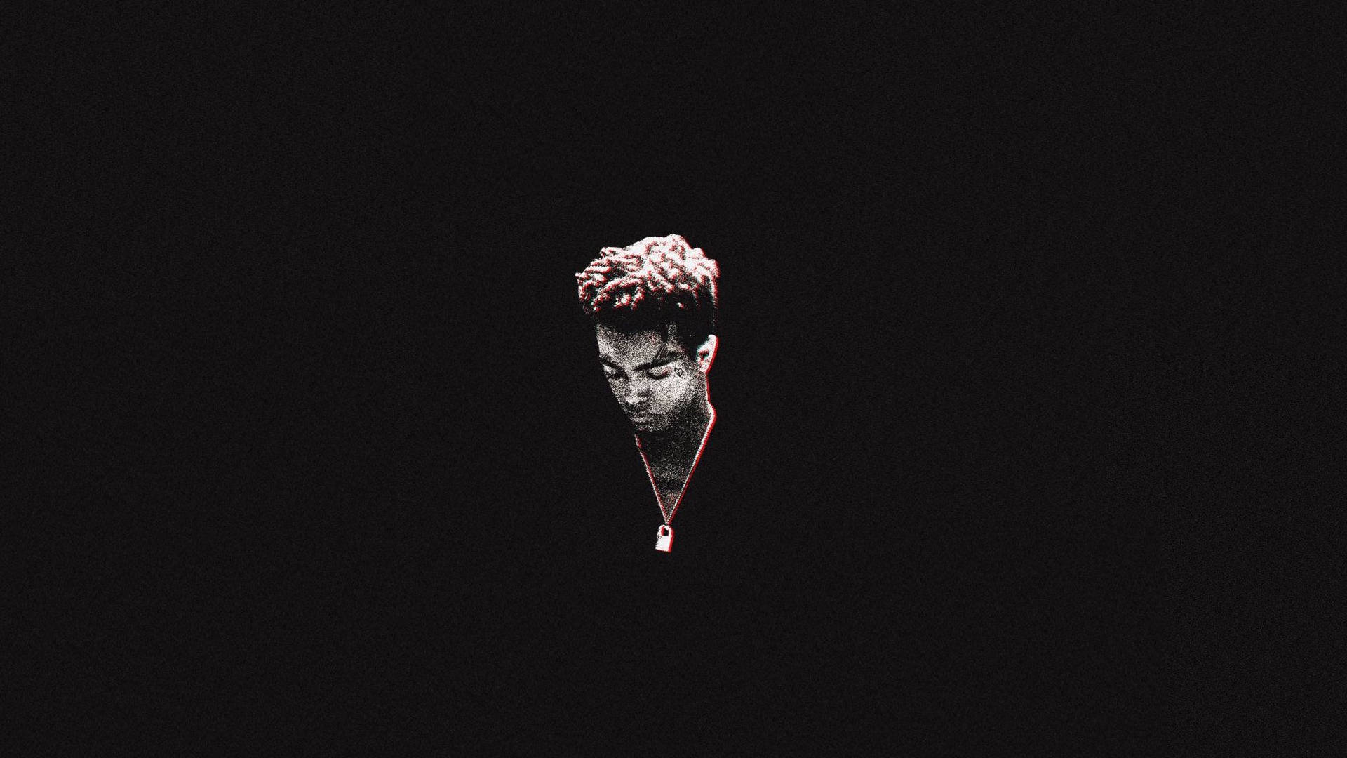 xxxtentacion 電腦 桌布 壁紙 — 一個孤獨的人，有著捲曲的頭髮和一條紅色項鍊，在漆黑的背景中微微發光。