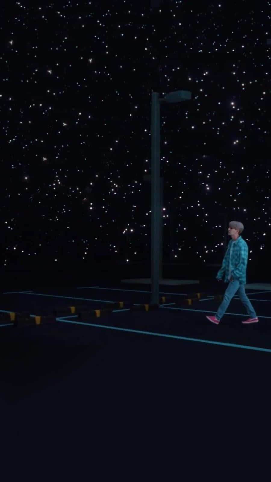 Bts Mv 桌布 壁紙 — 一個孤獨的人在一片星空下的空停車場行走，附近有一盞高路燈。