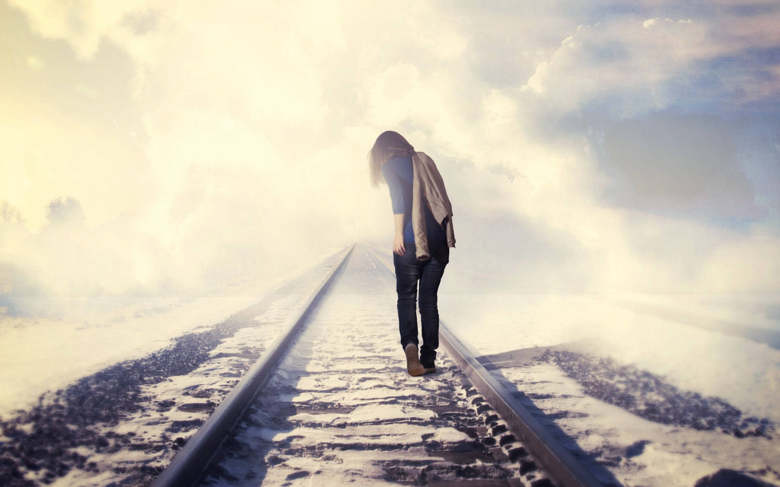 Alone 桌布 壁紙 — 一個孤獨的人在明亮朦朧的天空下沿著積雪的火車軌道走開。