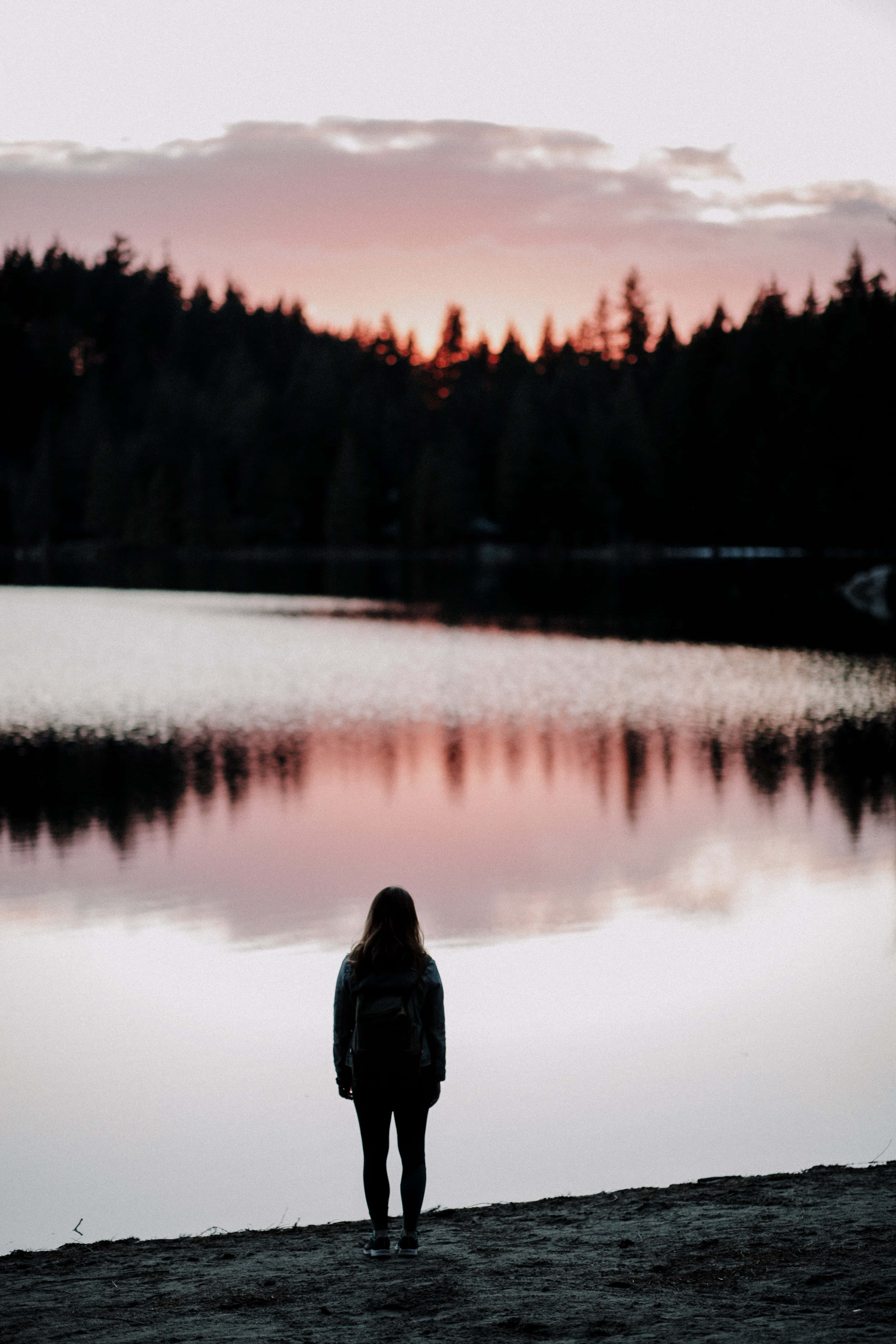 Silhouette 桌布 壁紙 — 一個孤獨的人在黃昏時以剪影出現，凝視著一個平靜的湖，湖面反射出火辣的粉紅和橙色天空。