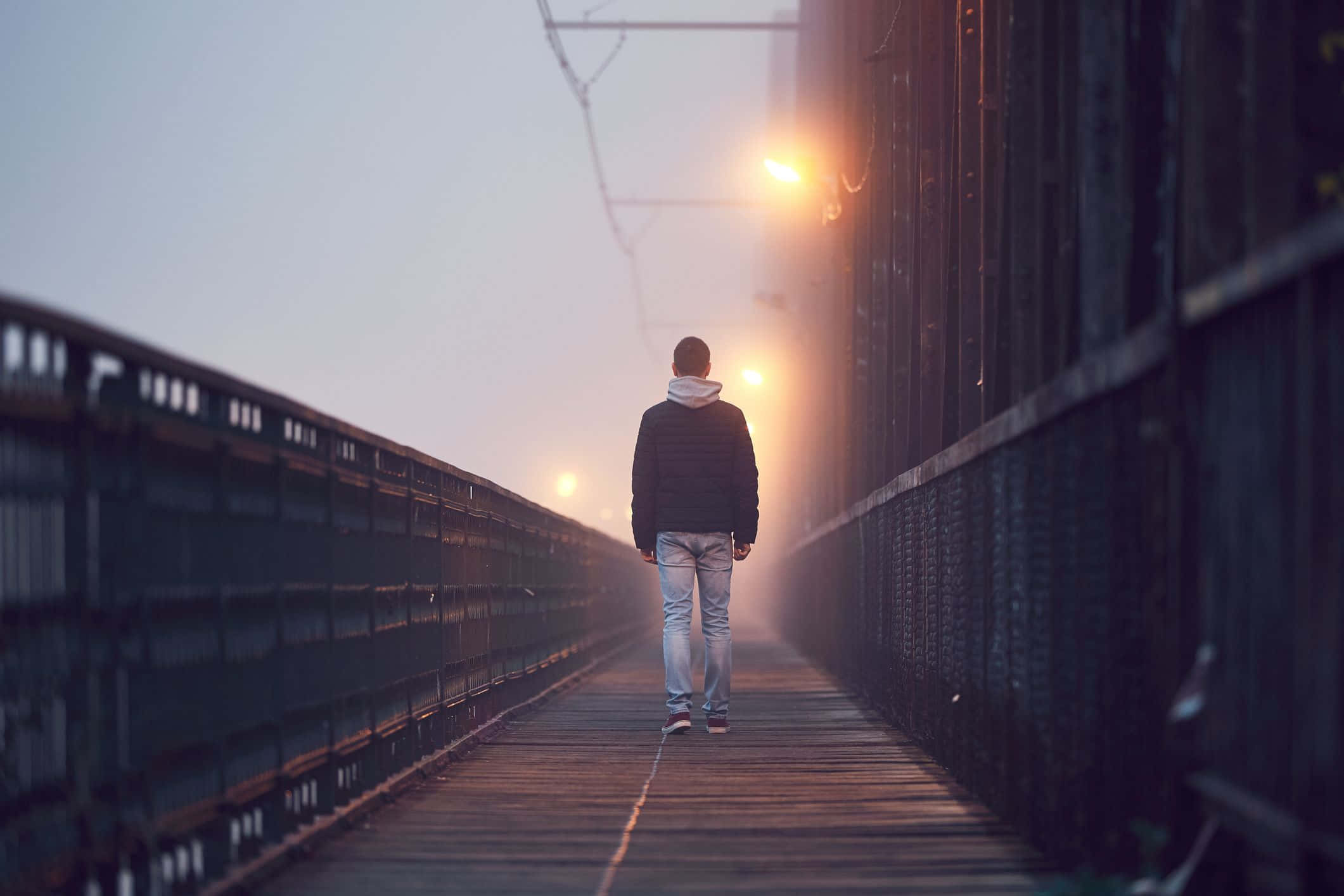 Lonely 桌布 壁紙 — 一個孤獨的人在黎明時分於霧濛濛的橋上走開，前方有溫暖的街燈亮著。