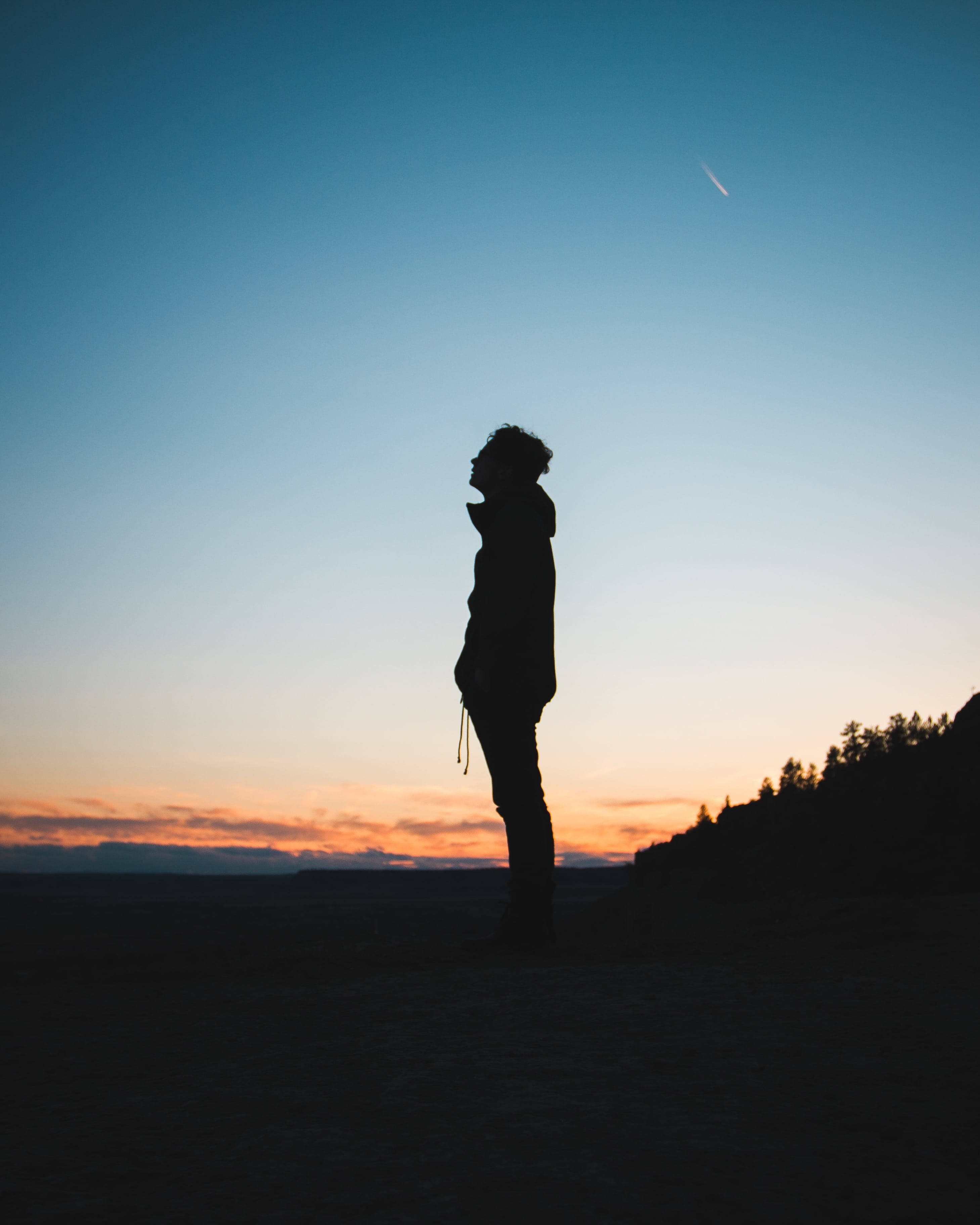 Silhouette 桌布 壁紙 — 一個孤獨的人影在暮色天空的襯托下形成剪影，一顆微弱的流星劃過頭頂。