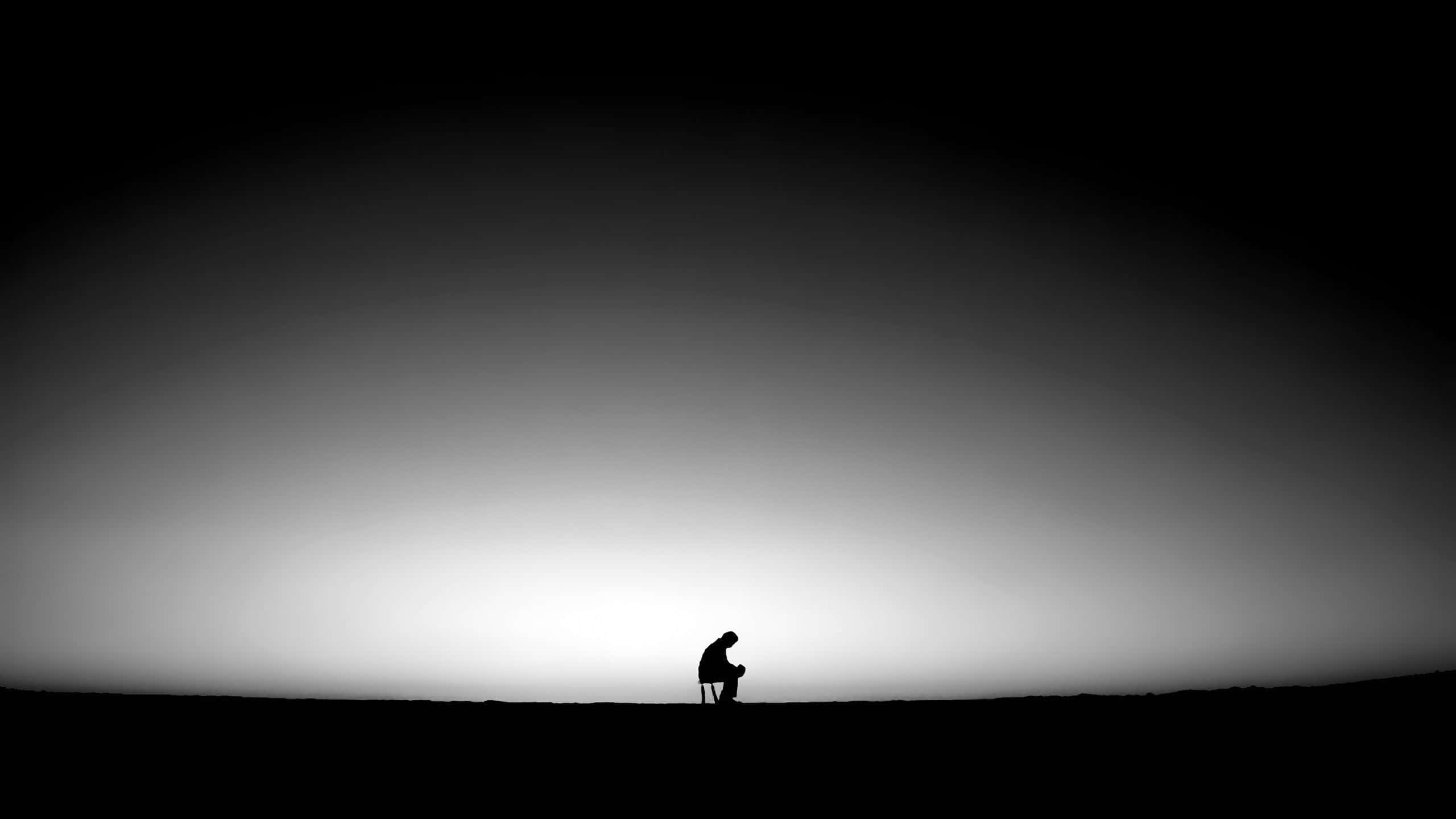 Lonely 桌布 壁紙 — 一個孤獨的人影蜷縮在椅子上，背景是暮色中廣闊的漸層天空。