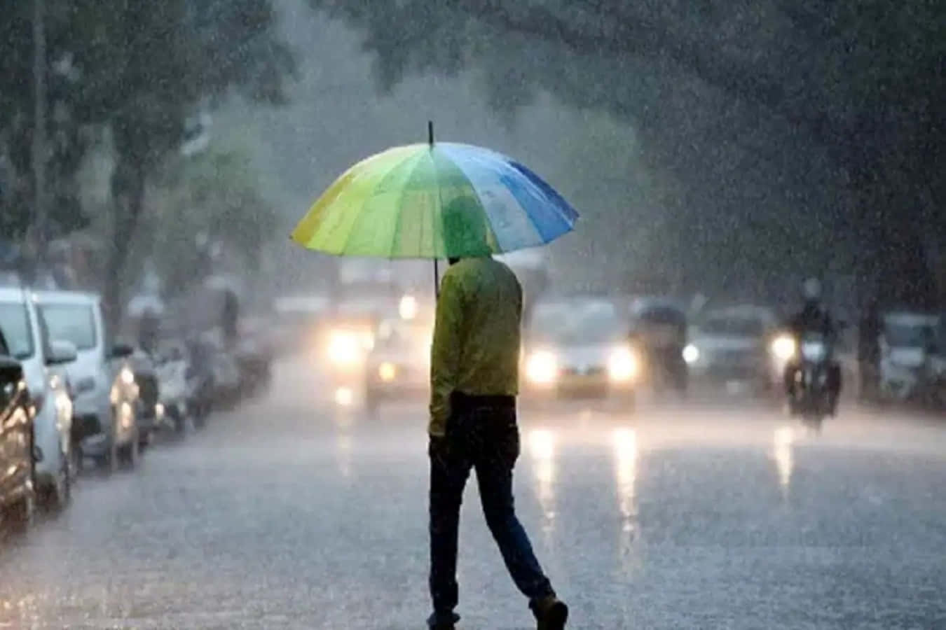 Raining 桌布 壁紙 — 一個孤獨的人走在濕漉漉的街上，撐著一把鮮豔的彩虹傘，車頭燈穿過傾盆大雨。