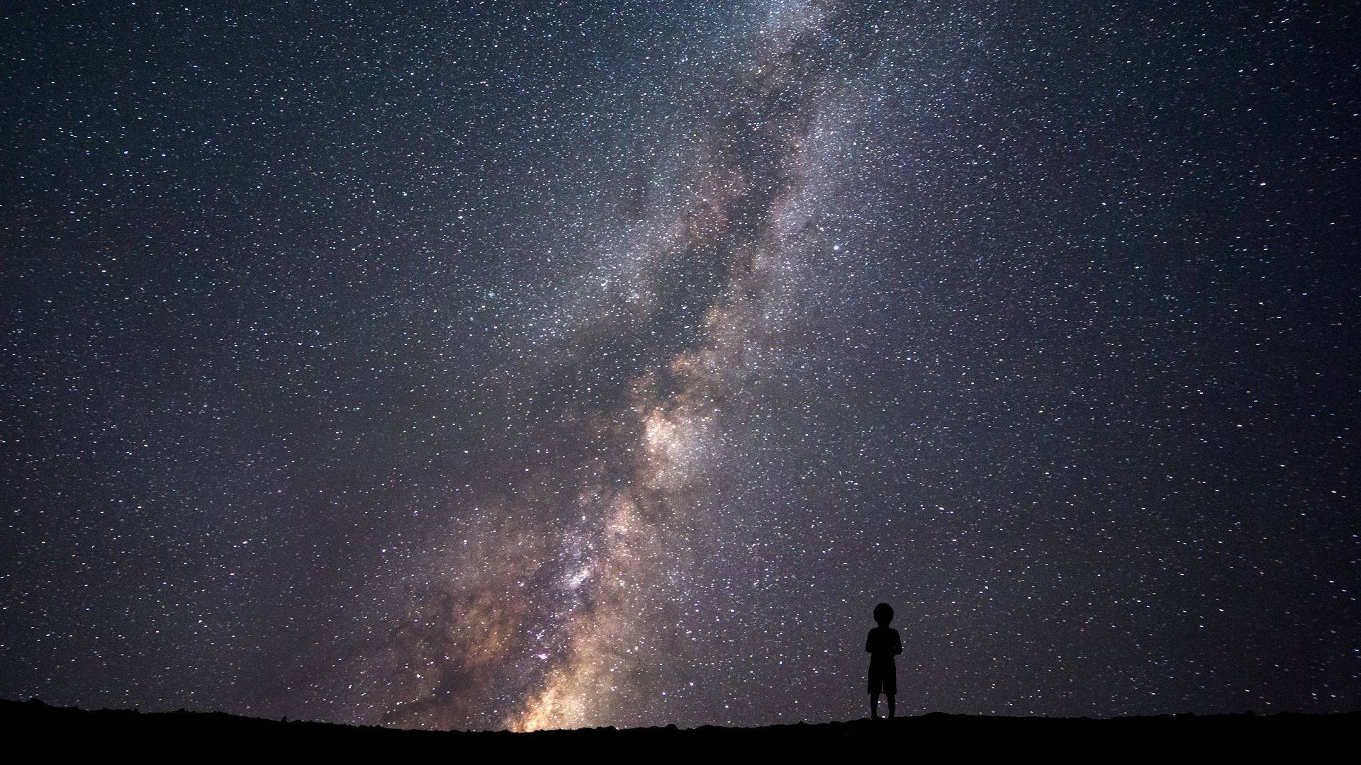 Star Space 桌布 壁紙 — 一個孤獨的剪影在令人驚嘆的銀河系下敬畏地站立，銀河散發著宇宙的光芒。