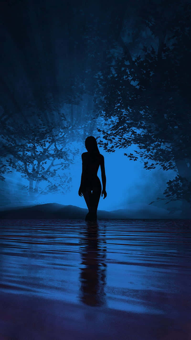 Silhouette 桌布 壁紙 — 一個孤獨的剪影在夜晚穿過霧氣籠罩的森林樹冠下發光的藍色水面。