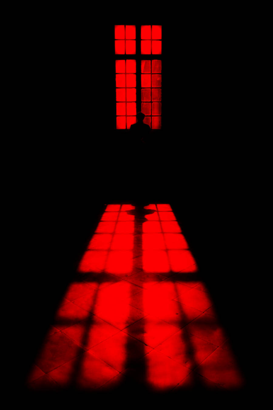 Silhouette 桌布 壁紙 — 一個孤獨的剪影站在一個發光的紅色窗前，在完全黑暗的地板上投射出鮮明的深紅色網格。