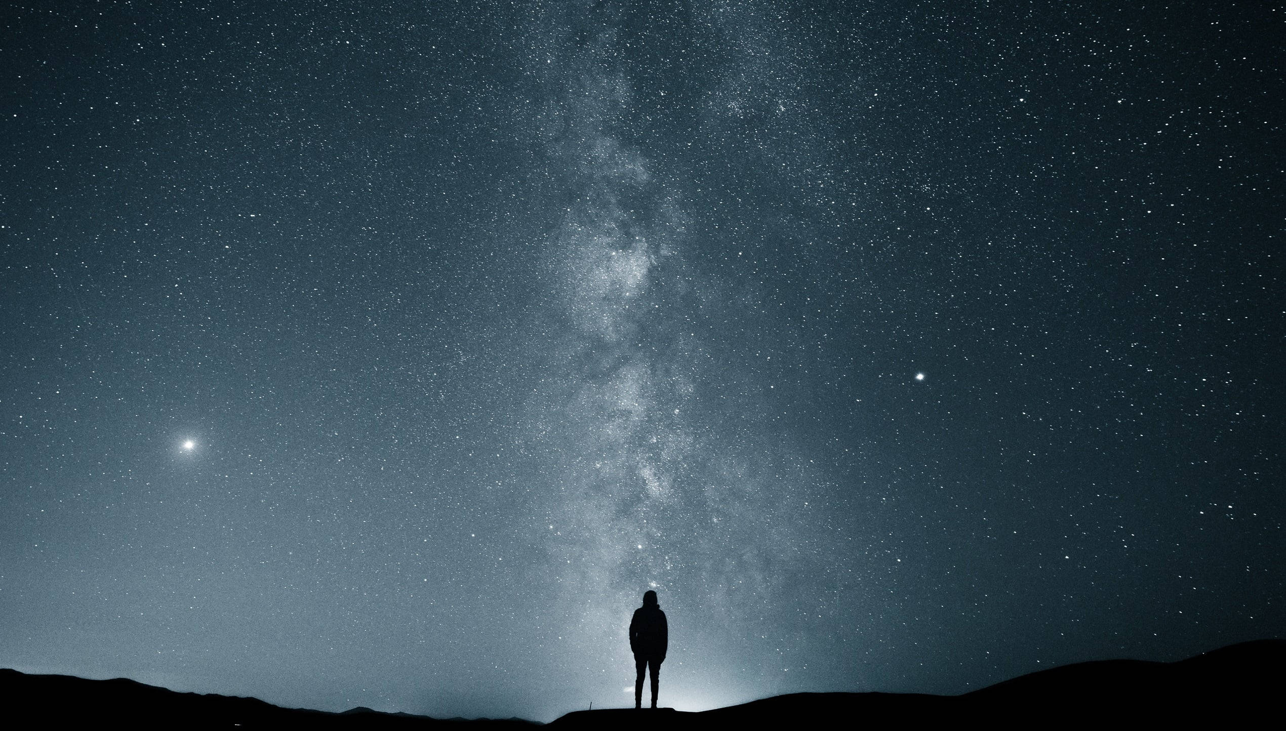 Alone 桌布 壁紙 — 一個孤獨的剪影站在山頂上，仰望充滿銀河系的壯麗星空。