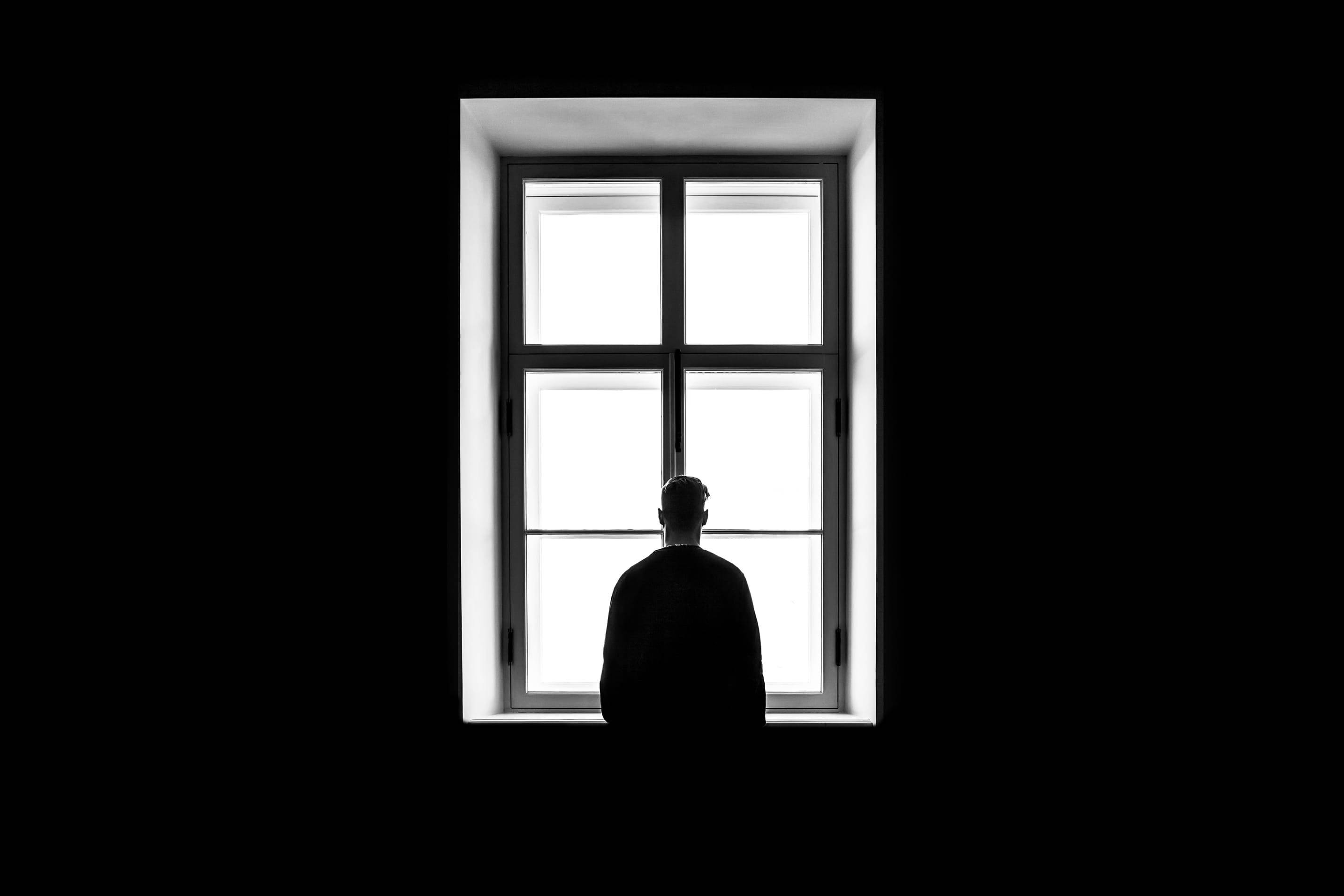 Alone 桌布 壁紙 — 一個孤獨的剪影被明亮的窗戶框住，背景是籠罩一切的黑色虛空。