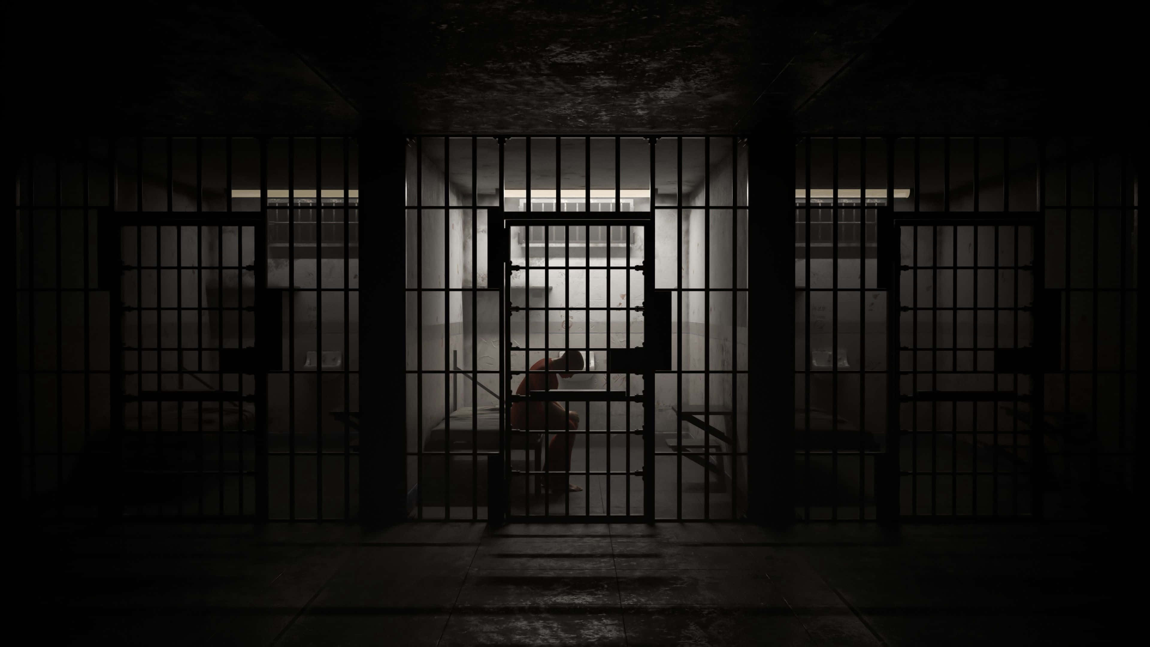 Prison Cell 桌布 壁紙 — 一個孤獨的囚犯蜷縮在昏暗的監獄牢房中，身後是沉重的鐵欄杆，周圍是壓抑的陰影和光禿禿的混凝土。