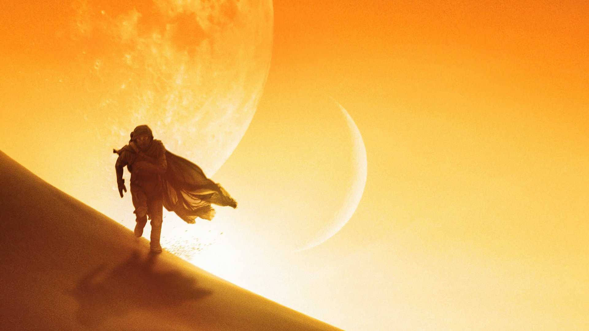 Dune 2021 桌布 壁紙 — 一個孤獨的太空人在巨大的橙色月亮和彎月下走過沙漠沙丘。